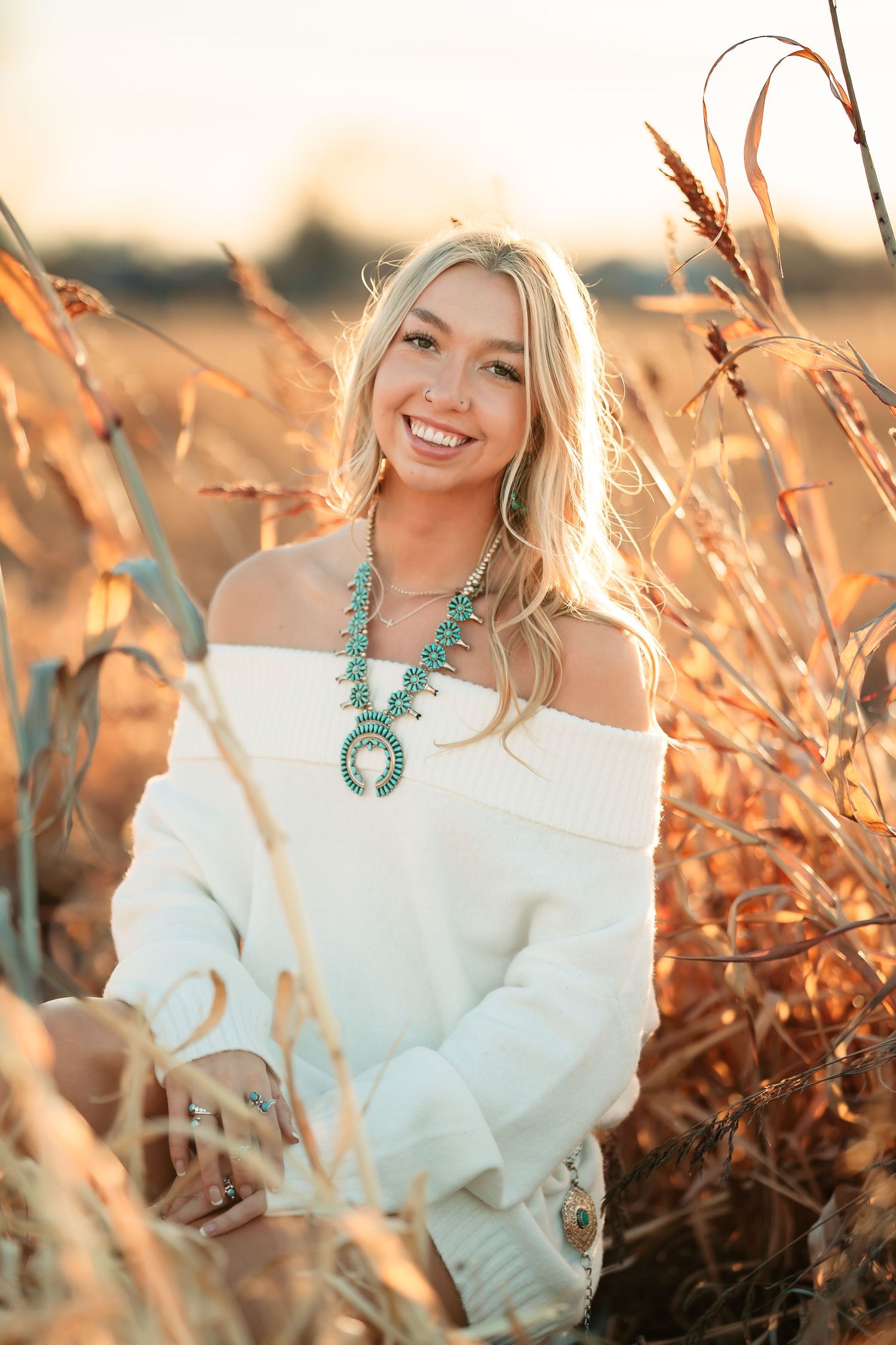 Outdoor portrait session in golden sunlight with white off-shoulder sweater and turquoise statement necklace.