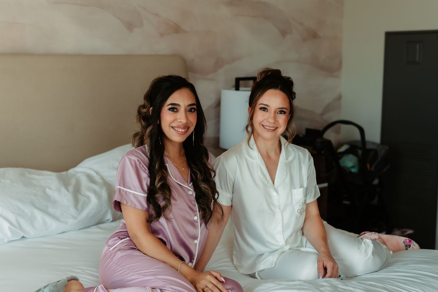 People in cozy sleepwear relax and smile together on a white bed during what appears to be a relaxed gathering.
