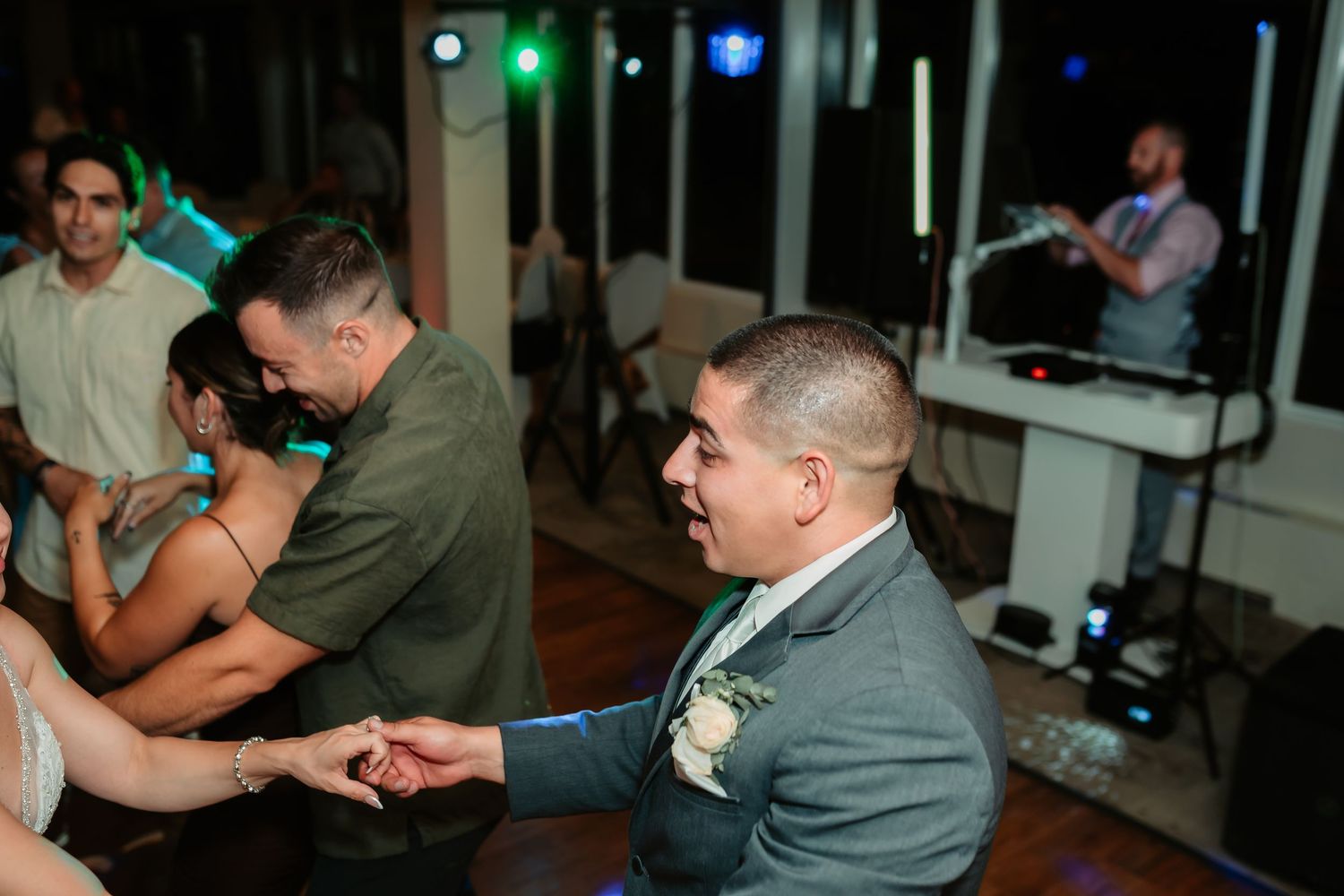 Wedding guests dancing and celebrating under colorful party lights.