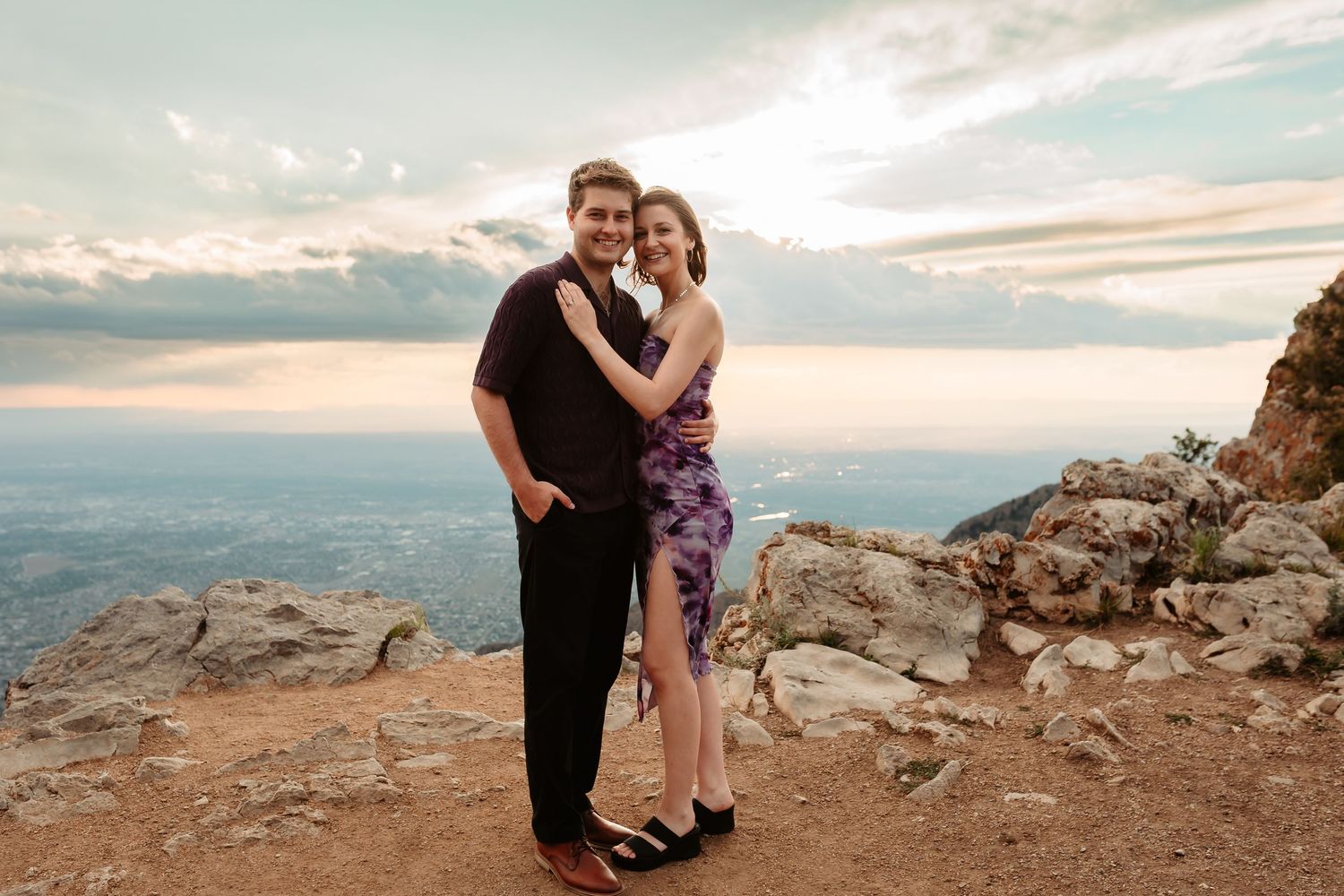 Couple sharing an intimate moment against a scenic mountain backdrop during sunset.