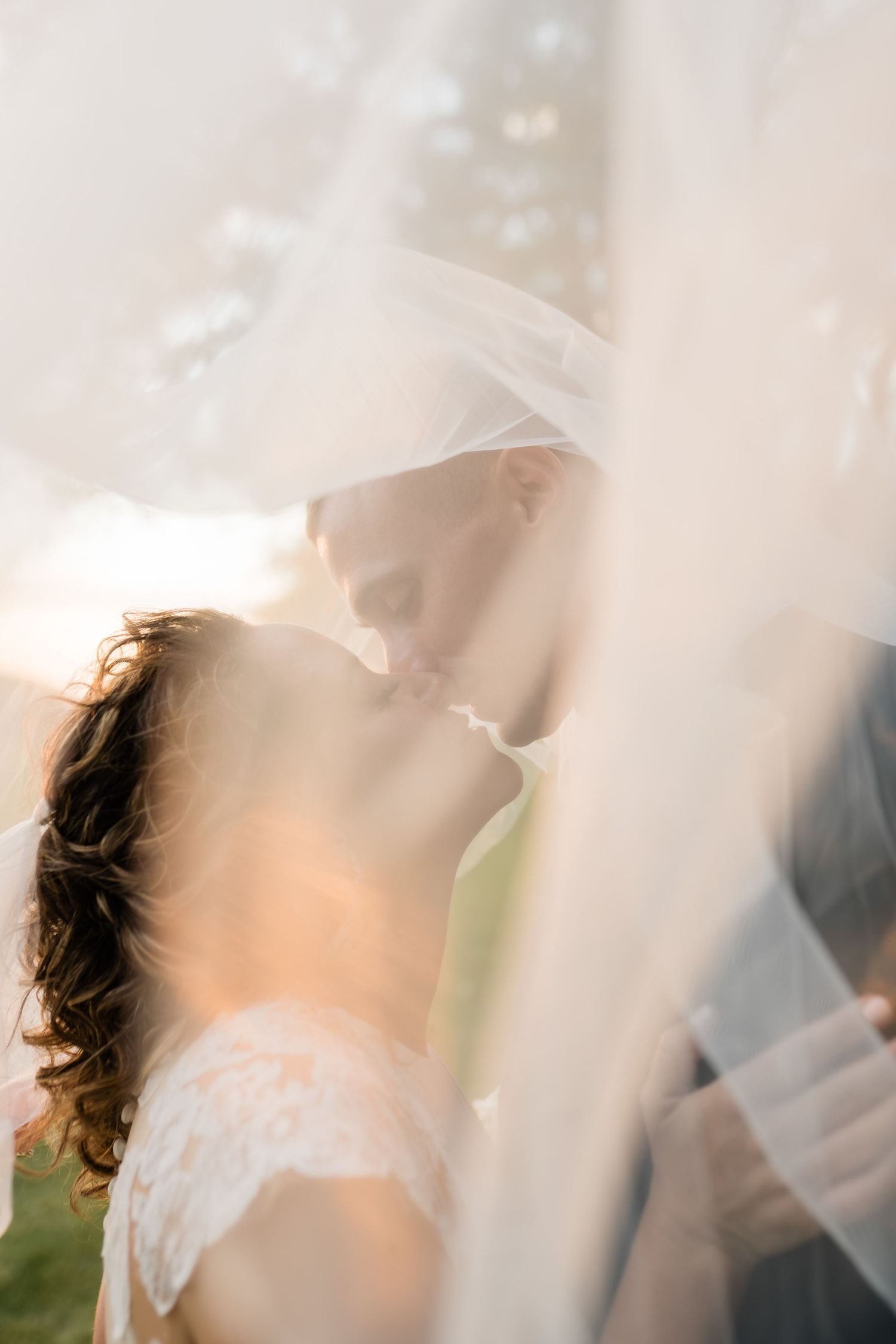 Soft ethereal wedding veil blowing in the breeze creates a dreamy romantic atmosphere at sunset.