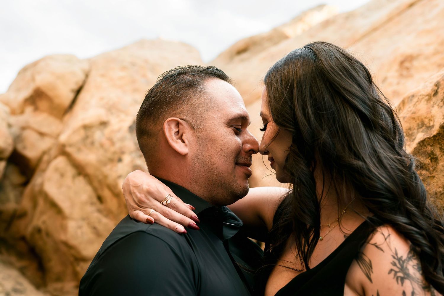 Couple sharing an intimate moment about to kiss among golden sandstone rocks outdoors.