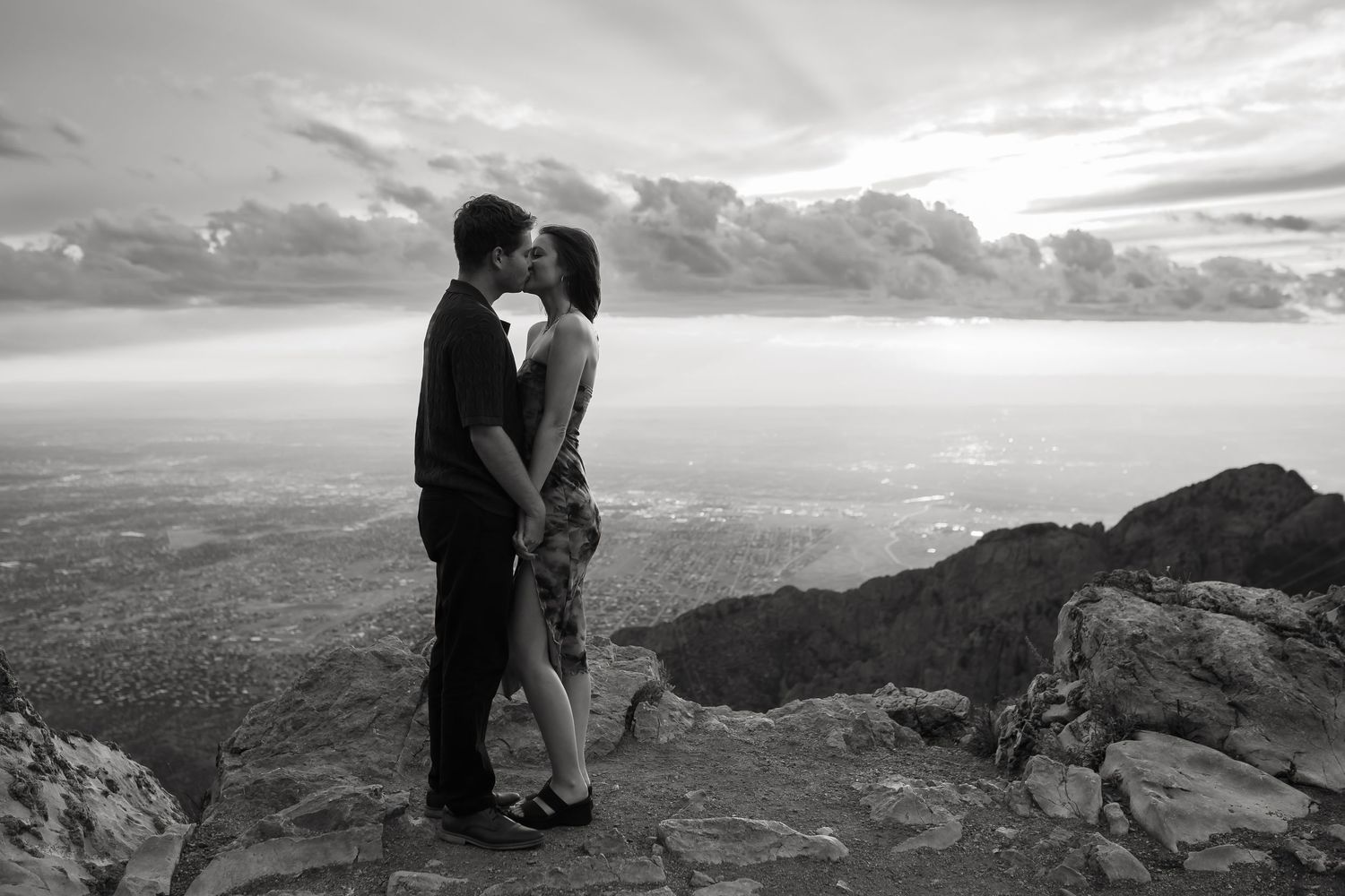 A panoramic mountain vista serves as backdrop for an intimate moment between two people.