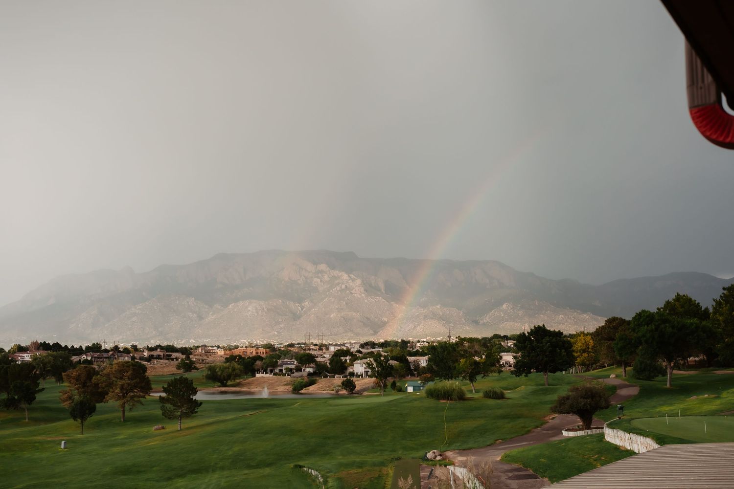 Panoramic view of mountains and golf course with storm clouds gathering overhead.