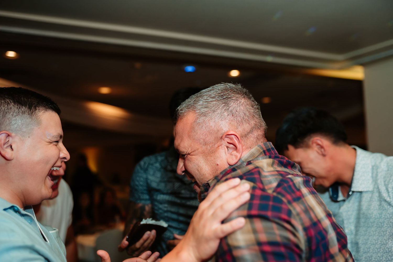 Group of enthusiastic party guests enjoying themselves on a dance floor at an indoor celebration.