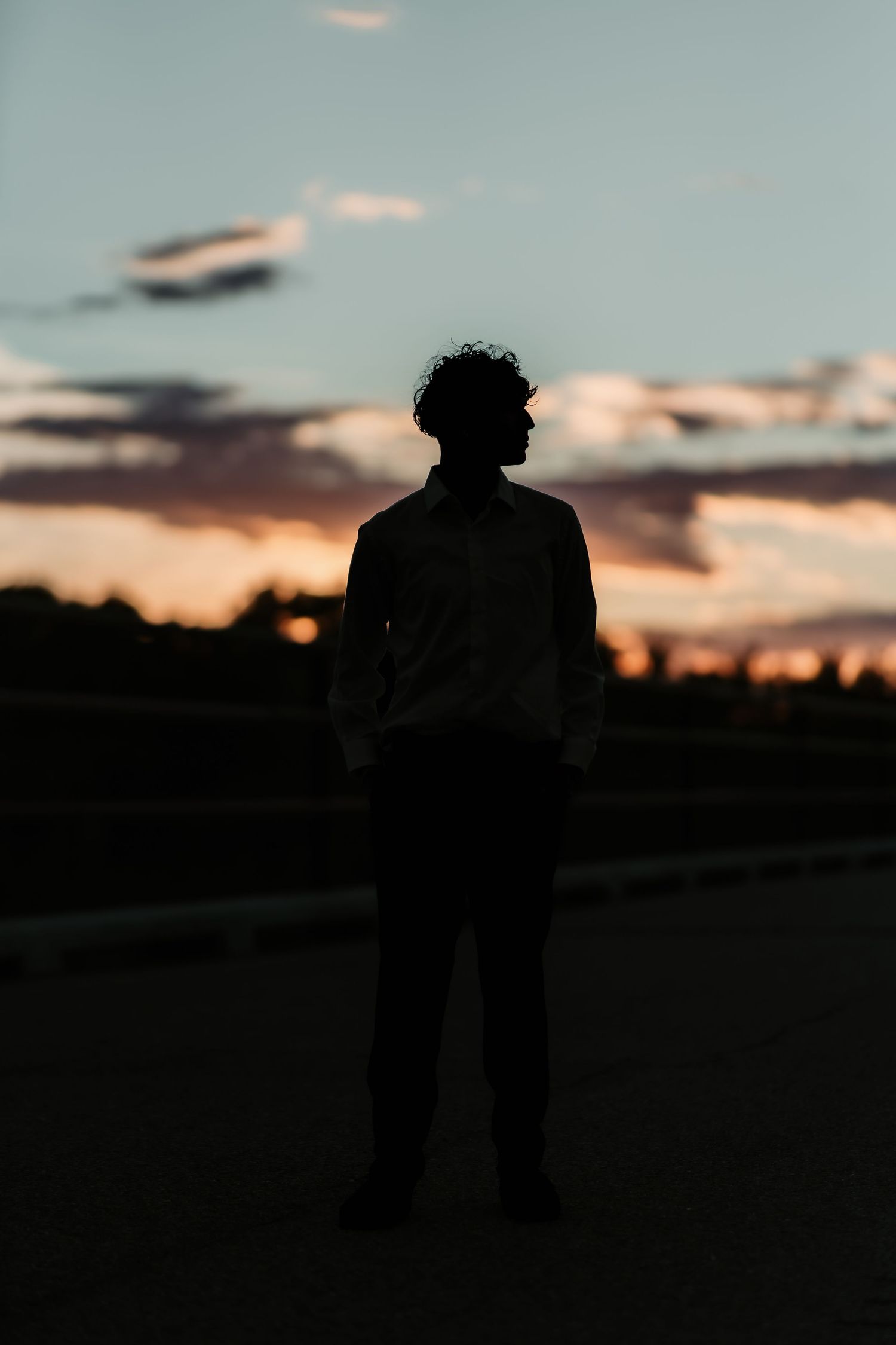 Silhouette of a person standing against a dramatic sunset sky with orange clouds.