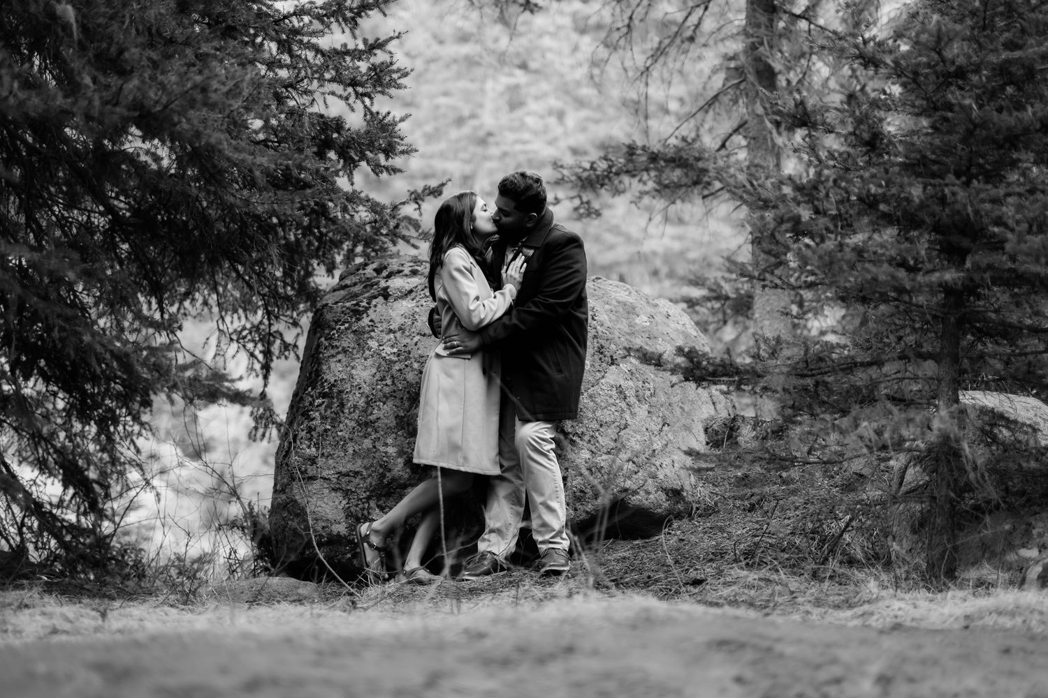 A black and white capture of a couple embracing on a forest path.