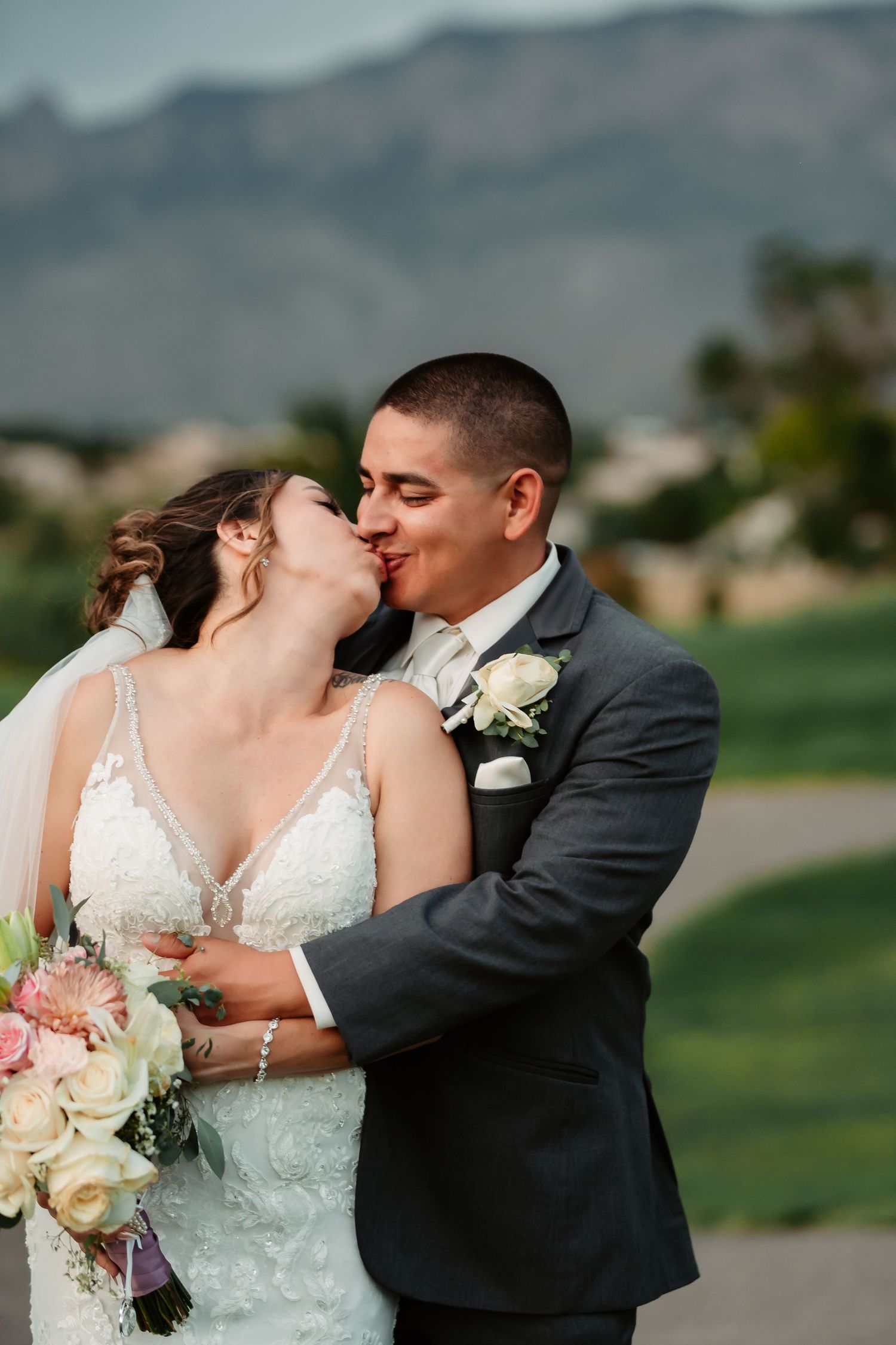 Romantic wedding portrait with pink and white bouquet against a mountain landscape.