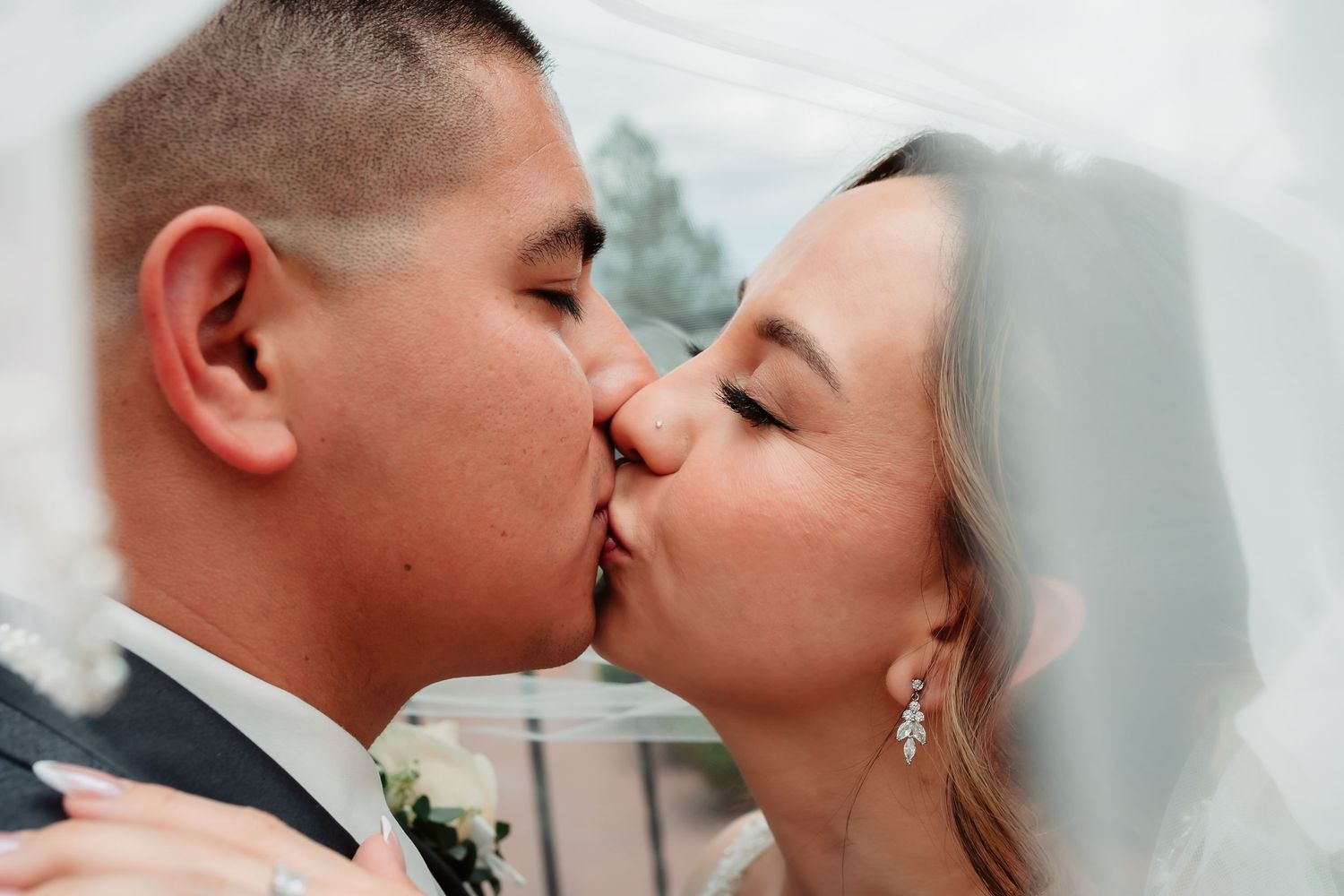 A romantic wedding day kiss shared under a delicate lace veil.