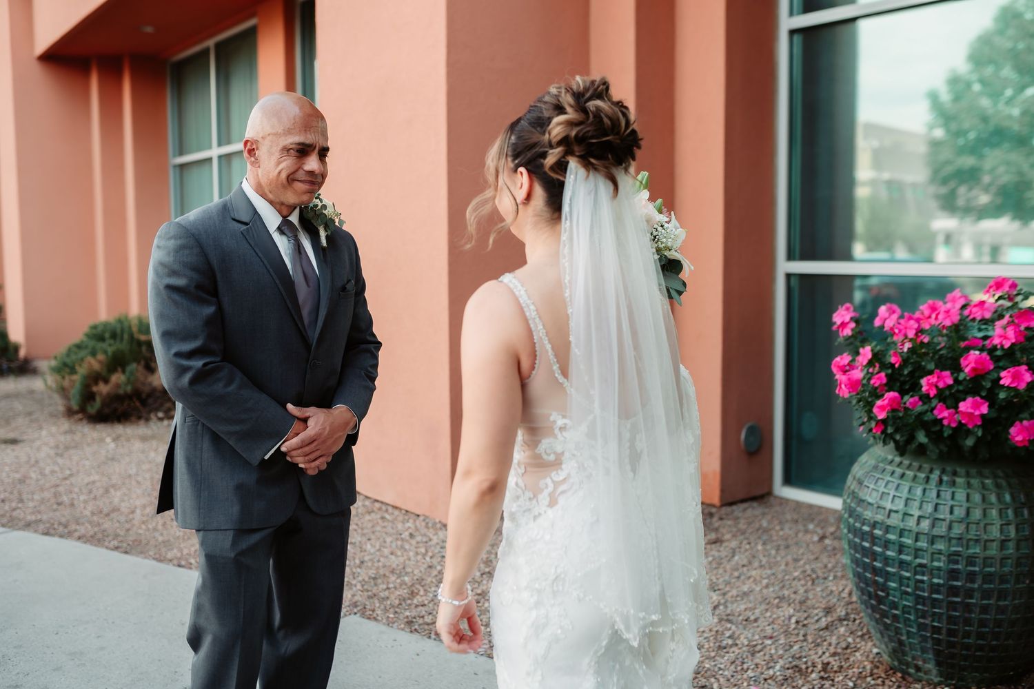 Wedding scene with elegant decor featuring coral-colored walls, glass windows and pink floral arrangements.