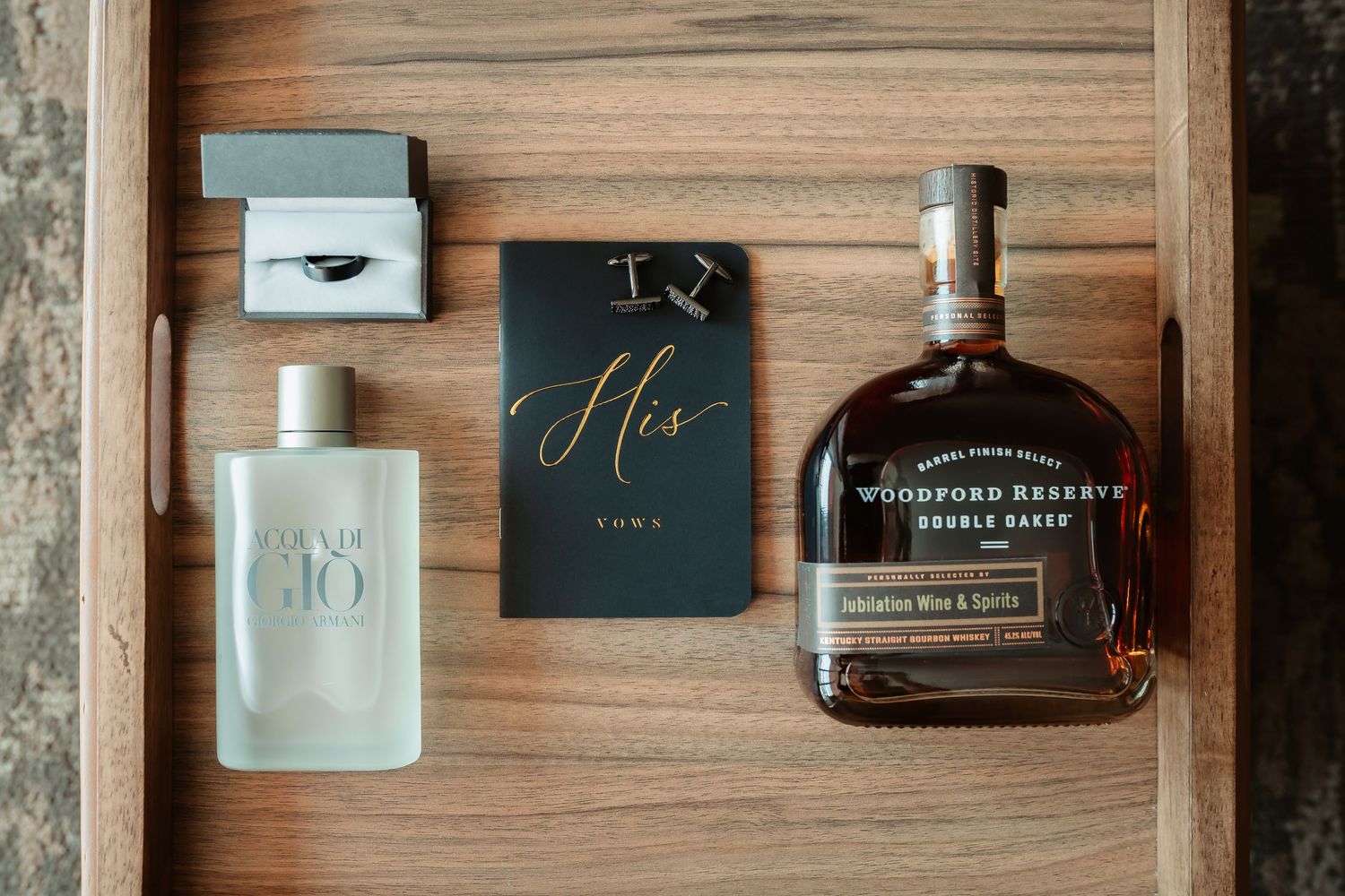 Wedding accessories including cologne bottles, cufflinks, and other personal items arranged on wooden surface.