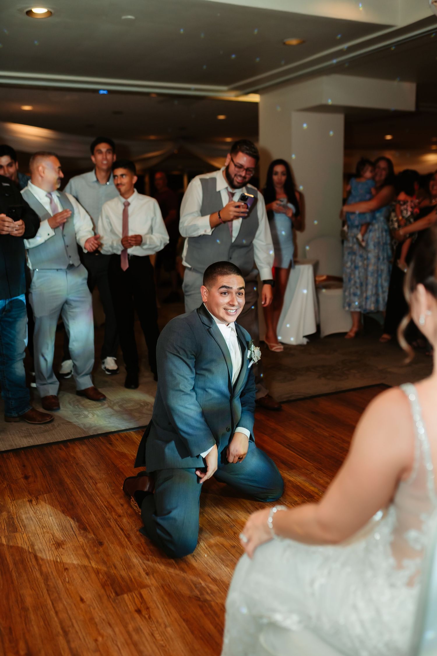 Wedding guests dance together on a hardwood floor during a reception celebration.