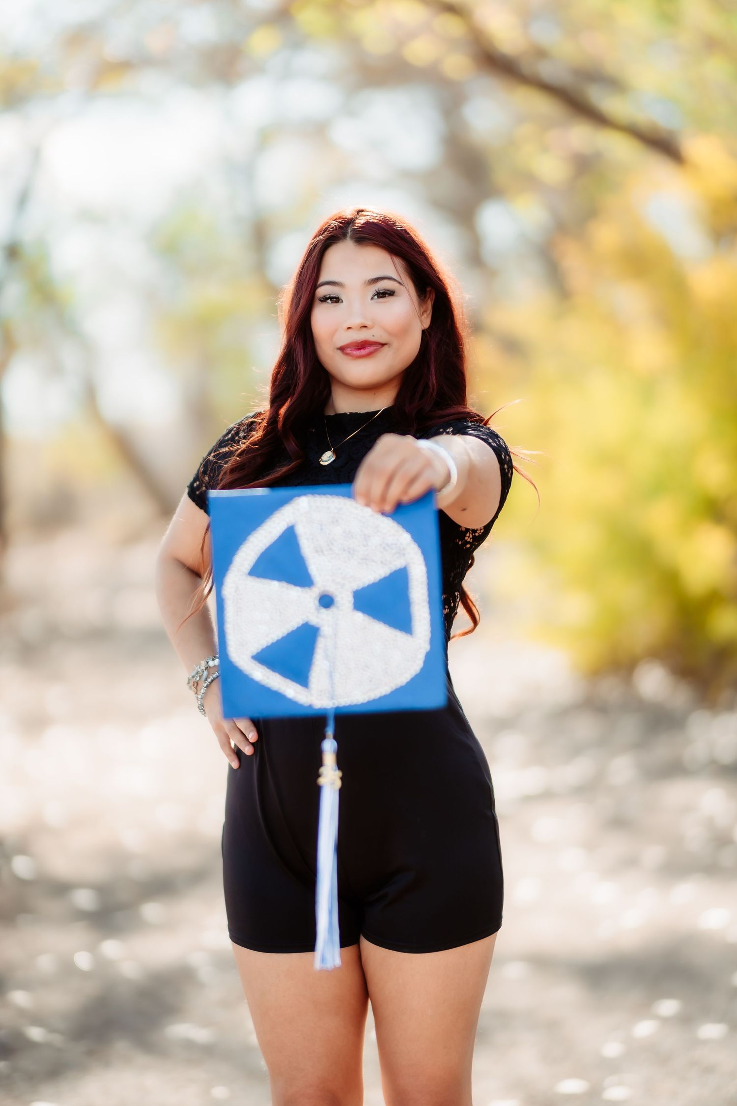 Outdoor photo showing person in black outfit holding blue and white directional sign.