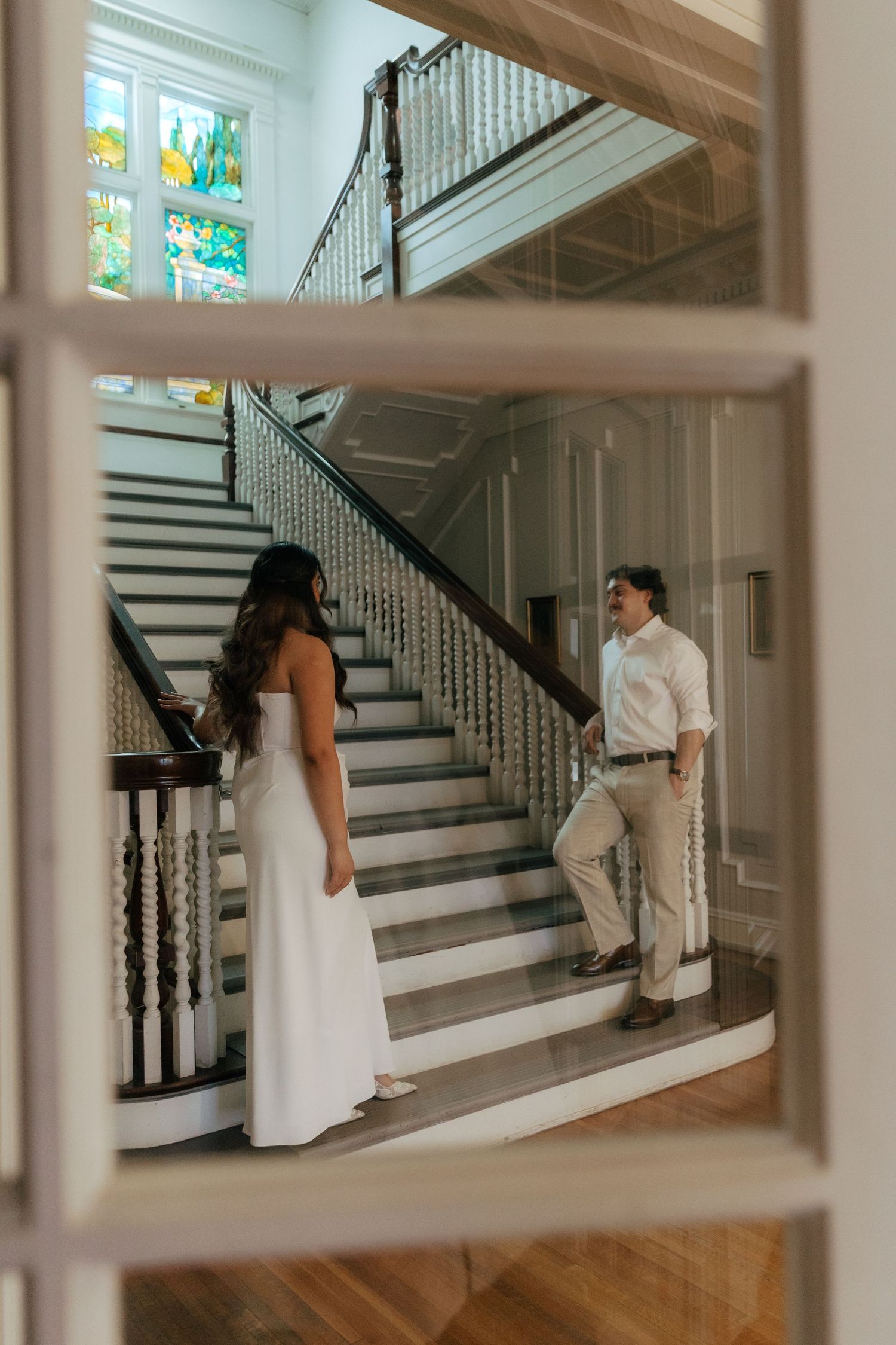Couple sharing a romantic first look moment on an elegant staircase inside a historic wedding venue.