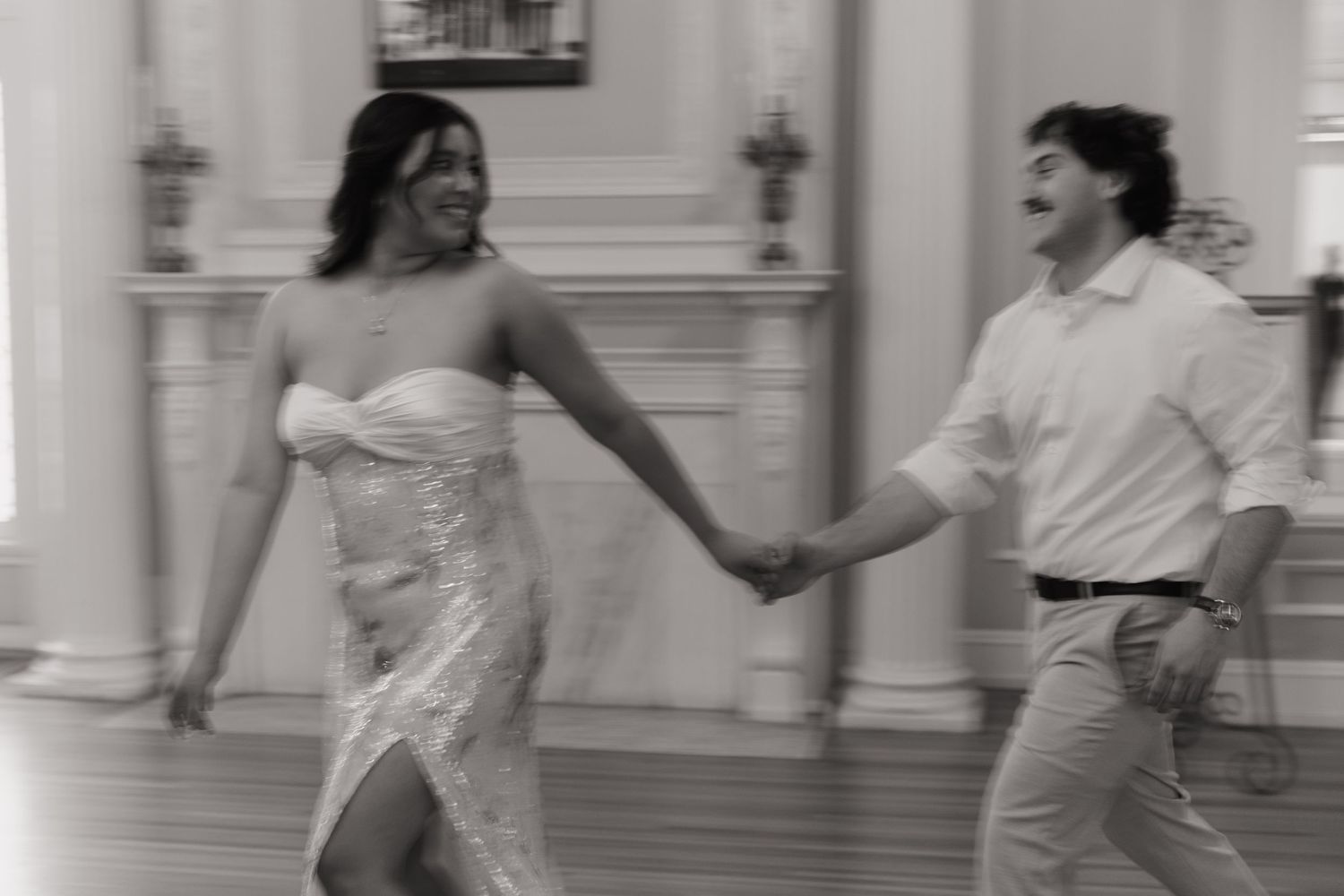 Bride and groom joyfully dancing together in black and white wedding reception photo.