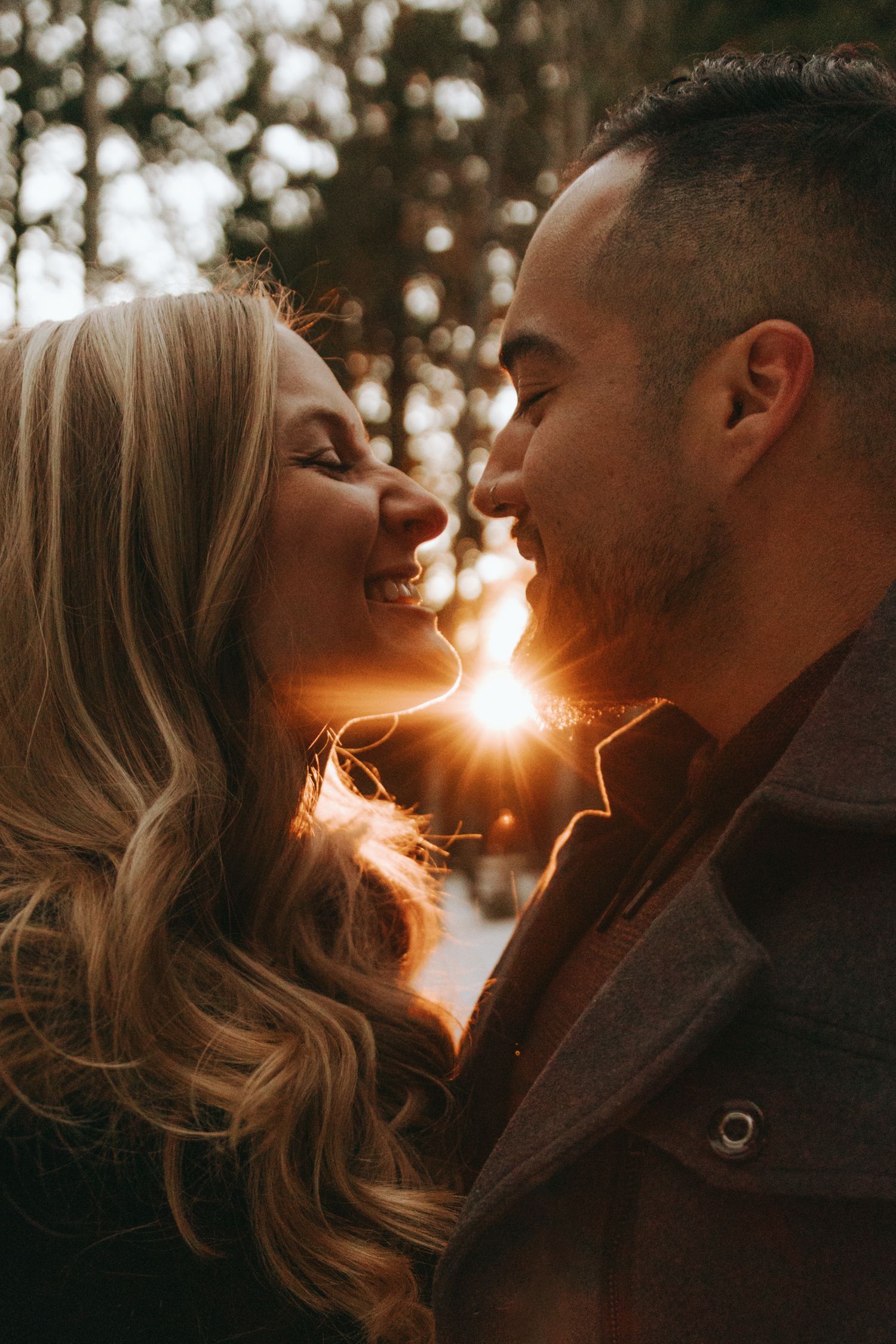 Couple sharing a romantic moment at golden hour sunset in a forest, warm light glowing between them.