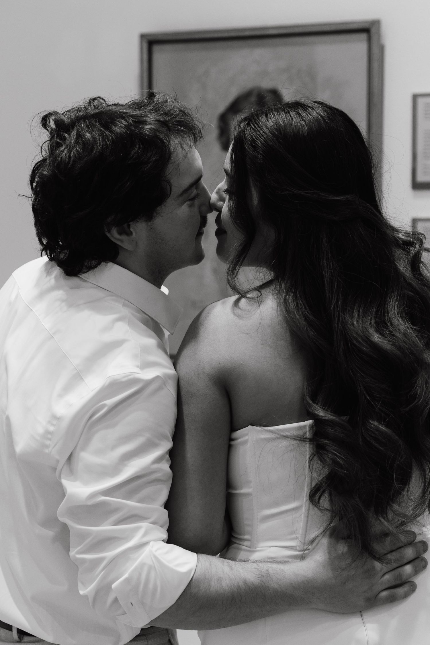 Black and white photo of a couple sharing a romantic moment, about to kiss, dressed in wedding attire.
