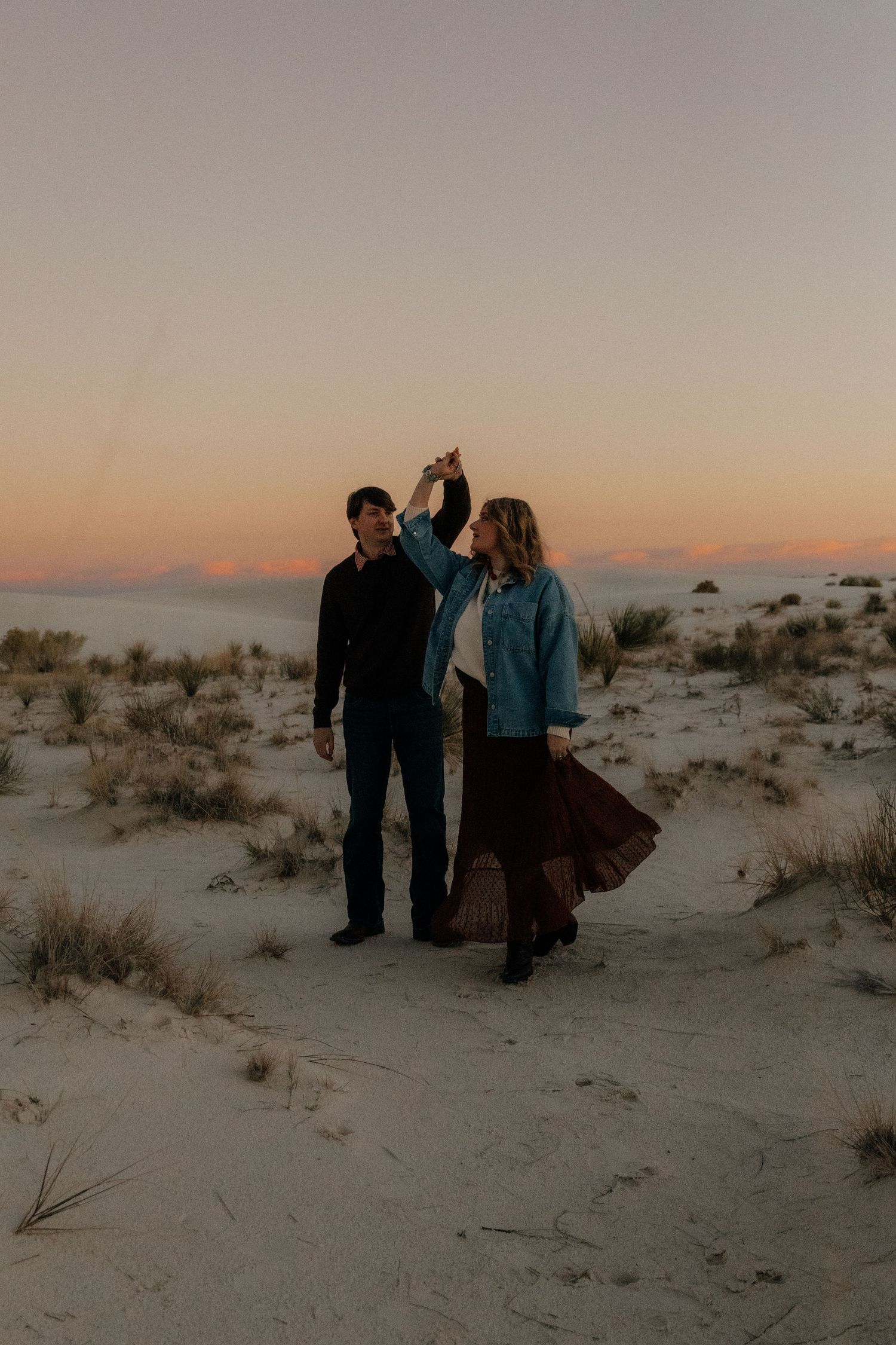 Couple dancing at twilight on white sand dunes in the desert.