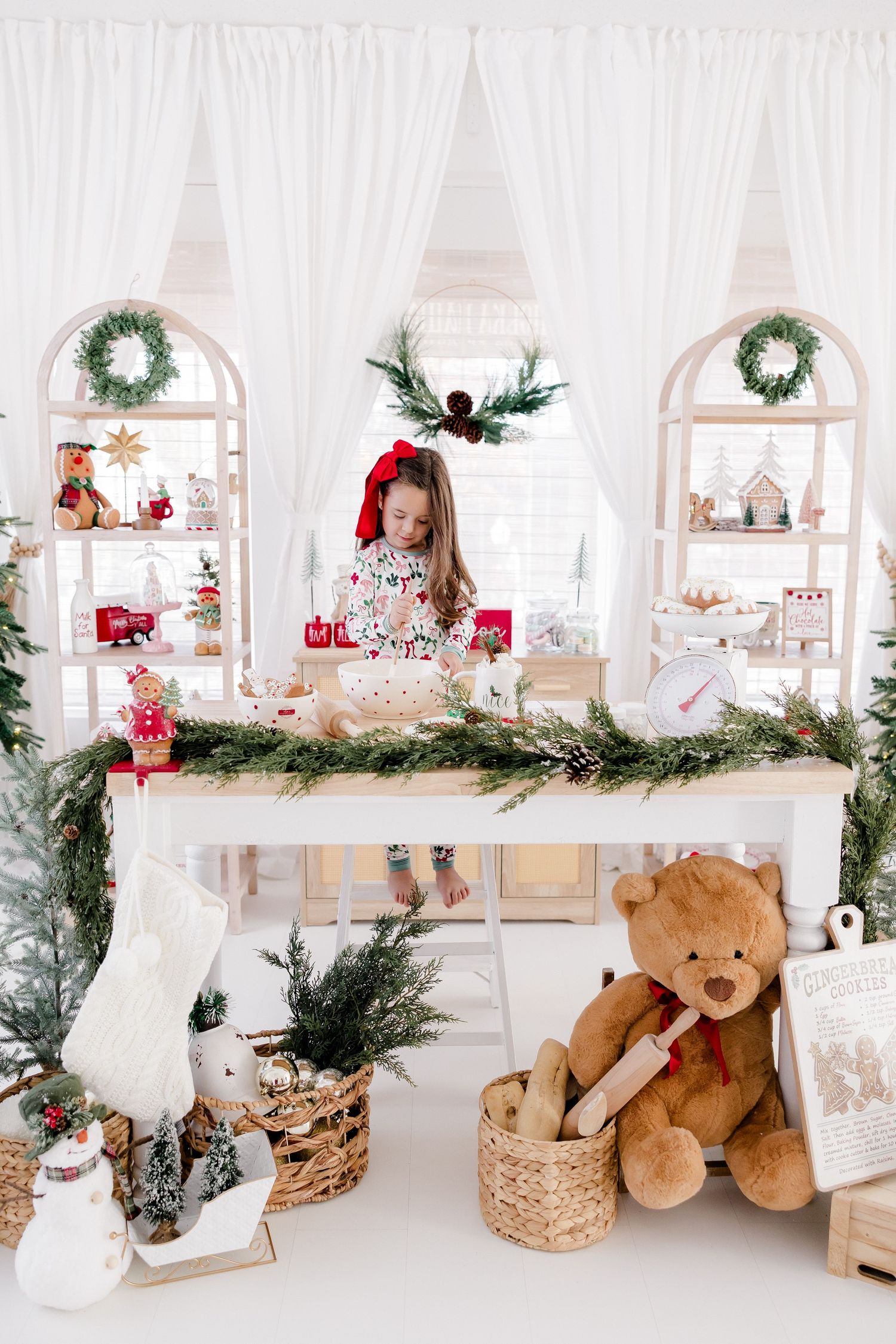 Holiday display shelf decorated with wreaths, greenery, teddy bears and Christmas decor.