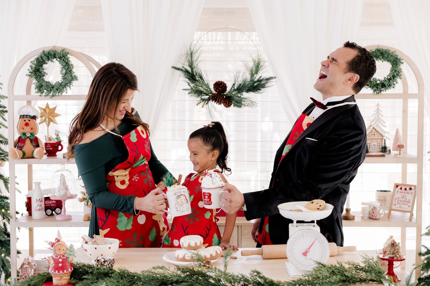 Holiday family portraits with coordinated outfits against white winter decor backdrop.
