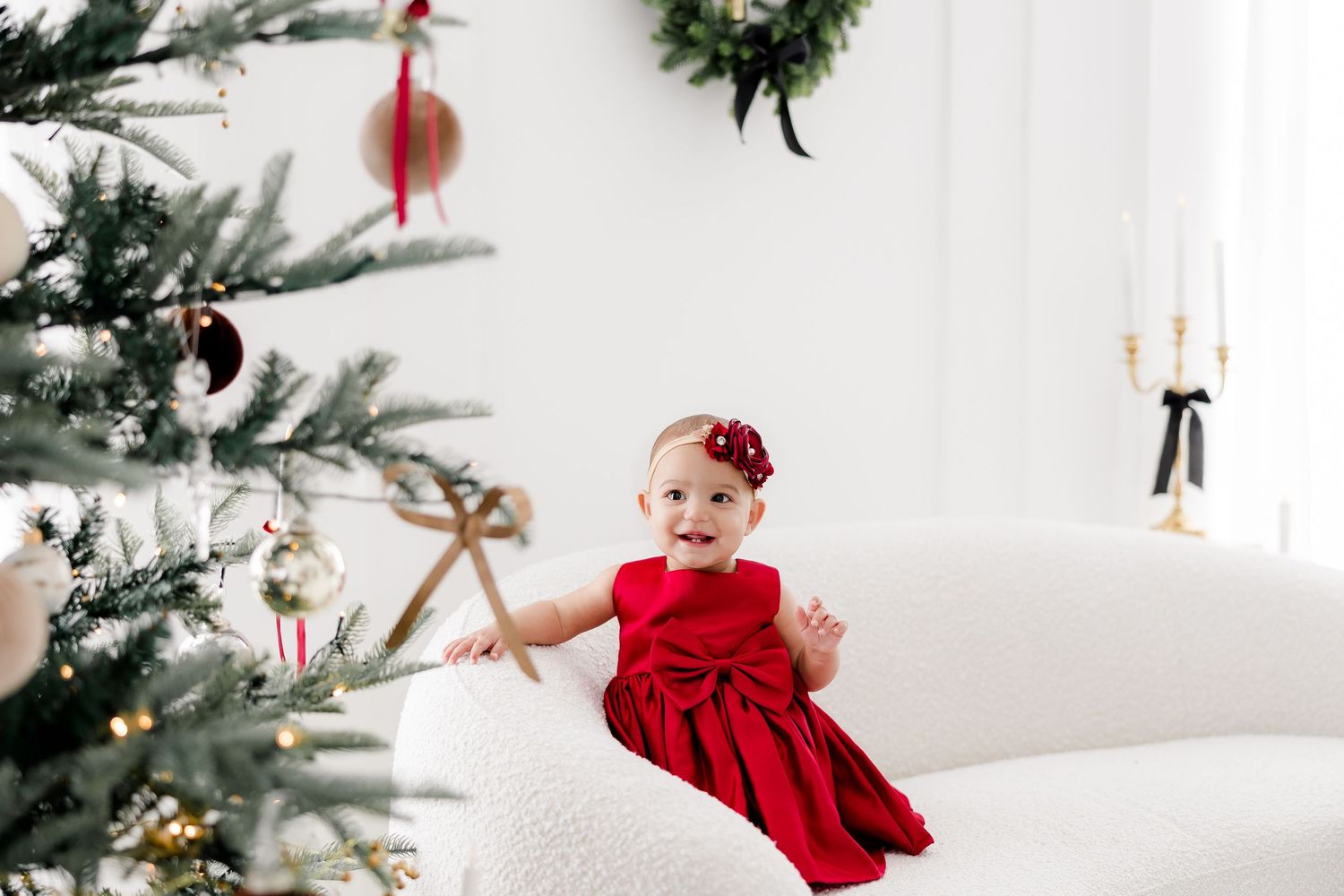 Christmas studio photography setup with white furniture and holiday greenery decorations.