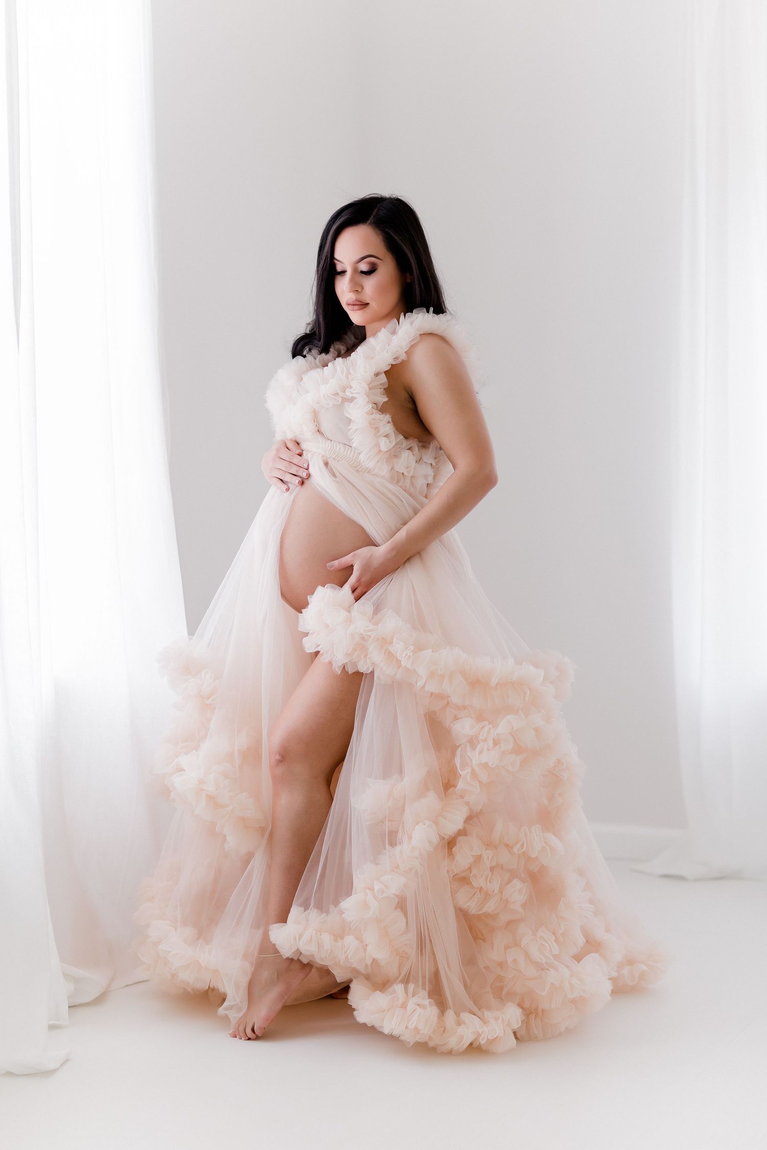 Intimate portrait session featuring blush pink ruffled tulle dress against white backdrop.