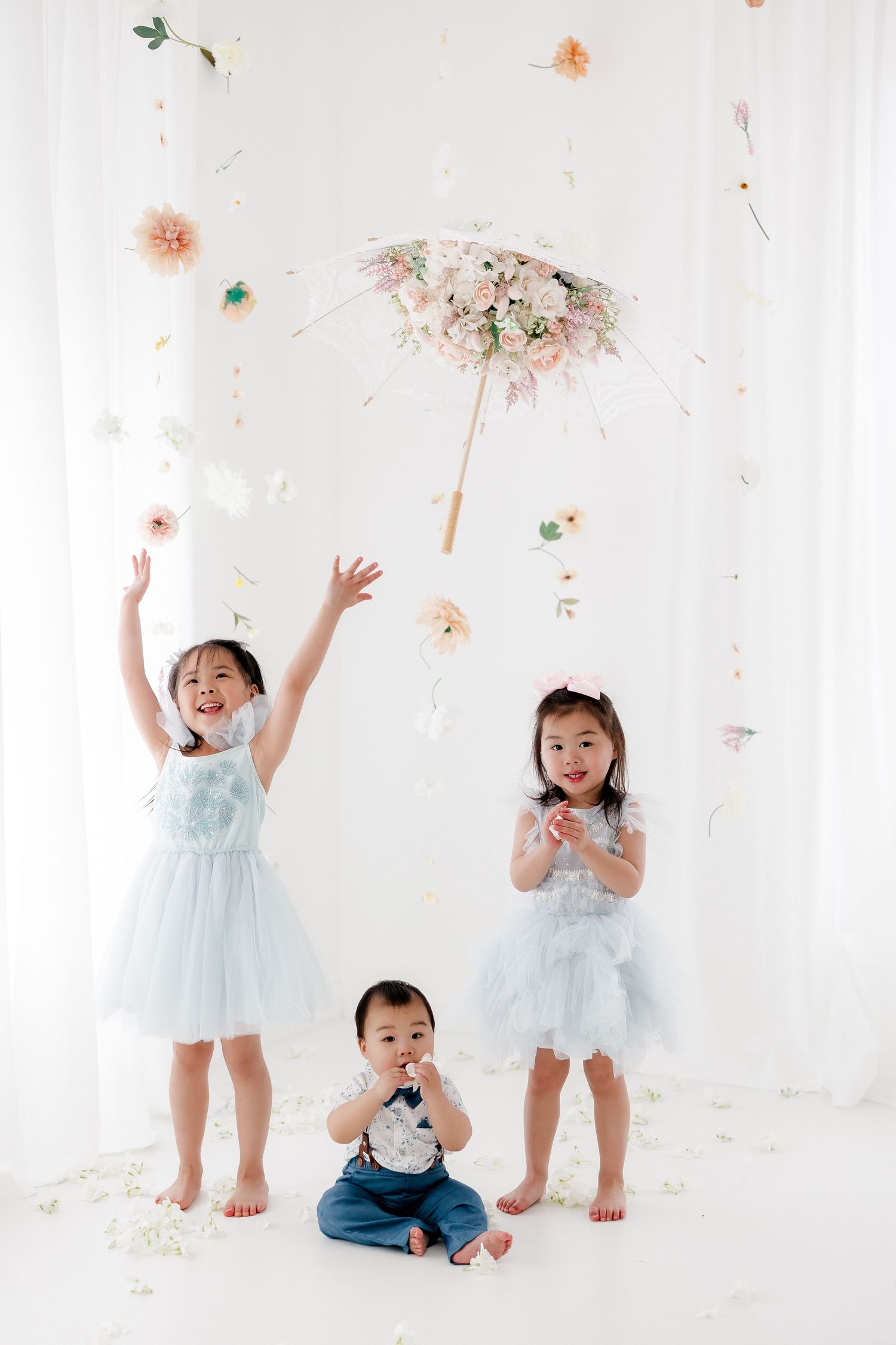 A series of playful photos showing children in light blue outfits tossing flower petals against a white backdrop.
