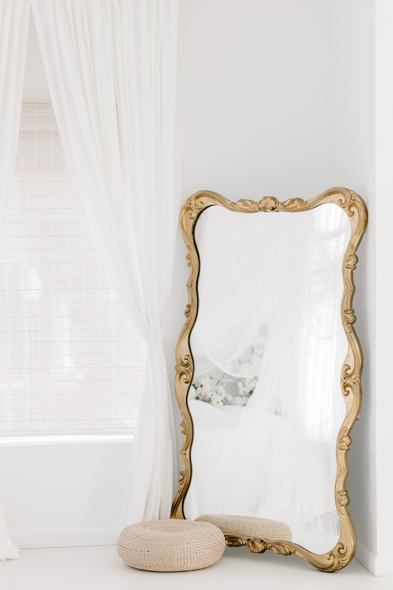 Elegant gold-framed mirror with ornate details against a white wall creates a vintage-inspired decorative accent.