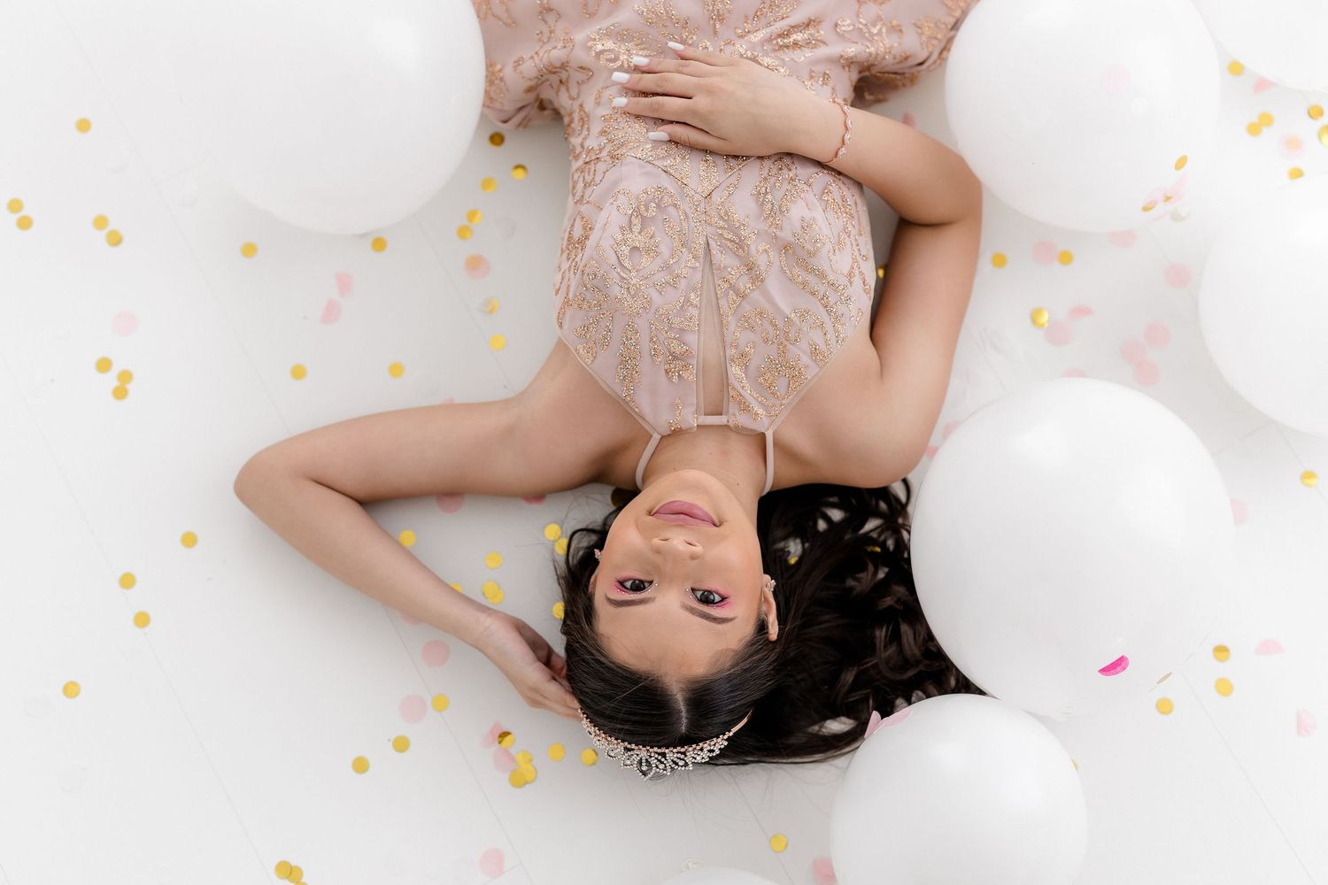 A person lies on a white surface surrounded by colorful confetti in a dreamy artistic portrait.