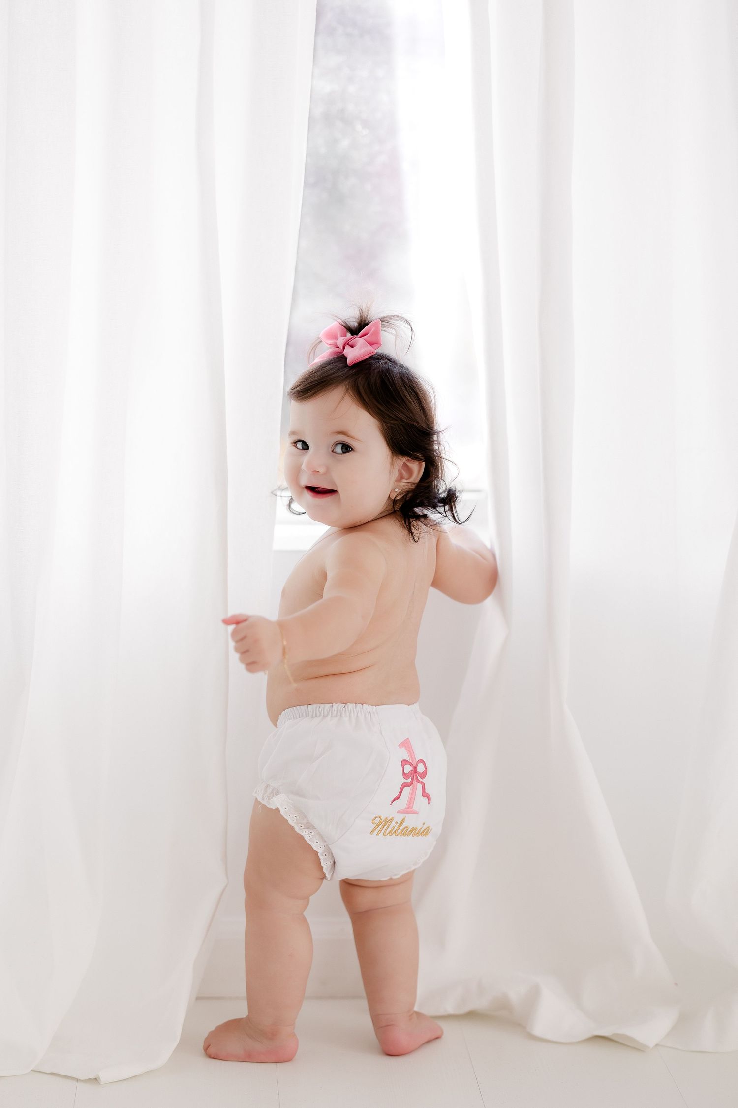 White curtains frame playful moment in bright studio setting.