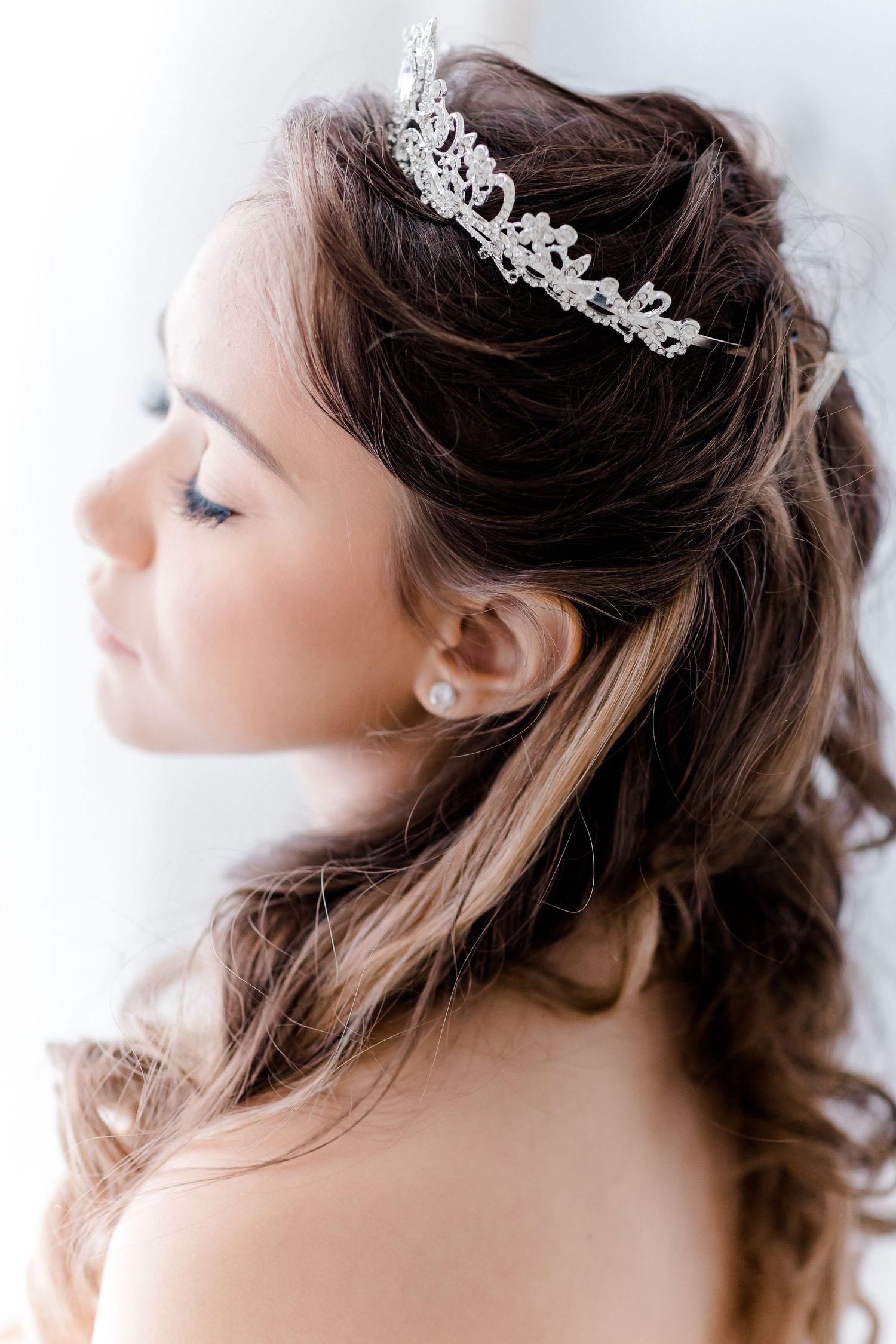 Elegant bridal hairstyle with delicate crystal tiara crown and soft waves styled for a wedding.