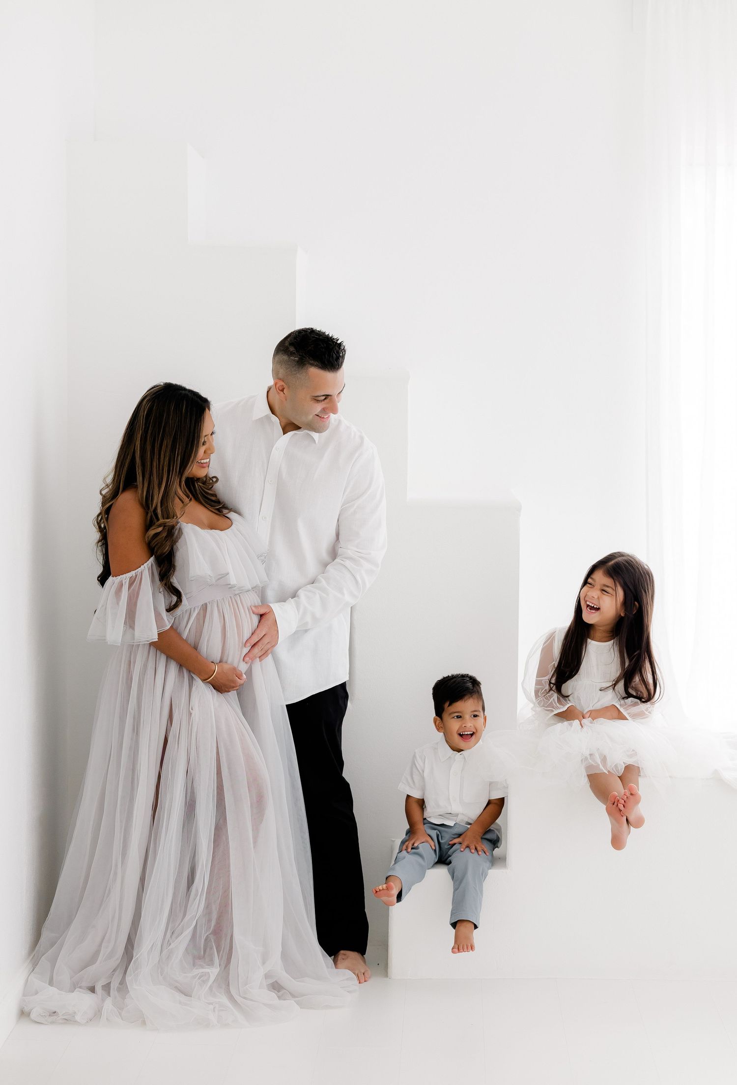 A series of minimalist family portraits against a white backdrop showing tender moments in matching white and gray attire.