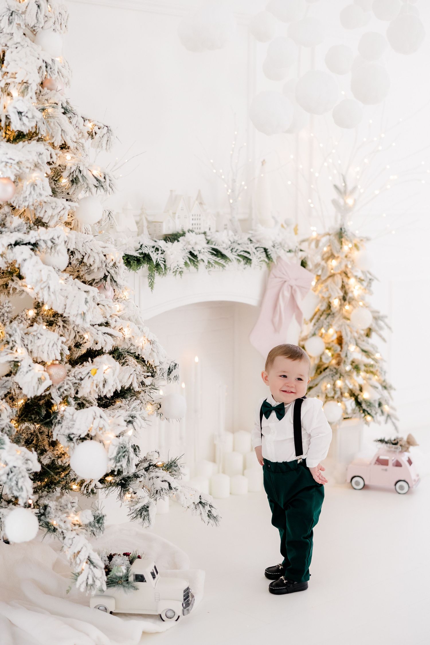 White and gold Christmas theme photography setup with decorated trees and white backdrop.