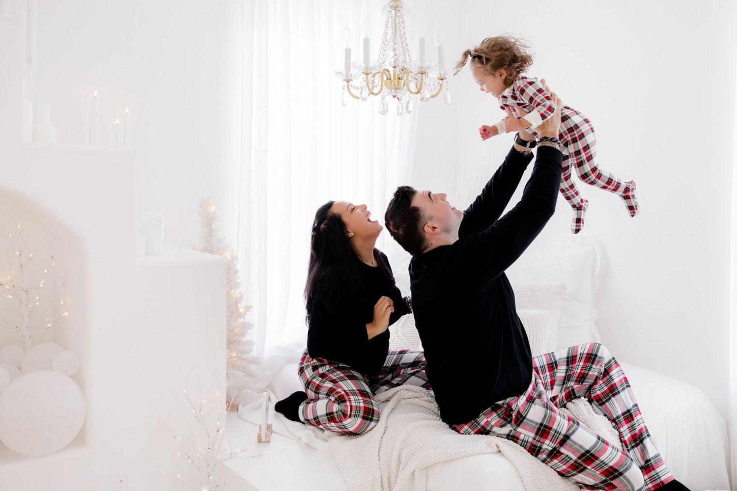 Family holiday photoshoot featuring matching plaid pajamas in a bright white setting.