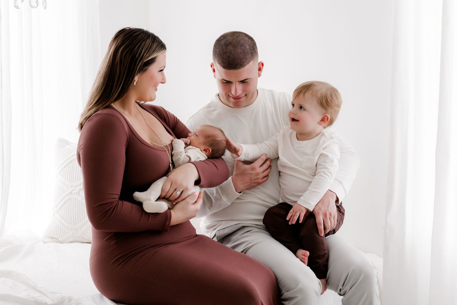 Maternity photo session in brown dress showing intimate family moments on white backdrop.