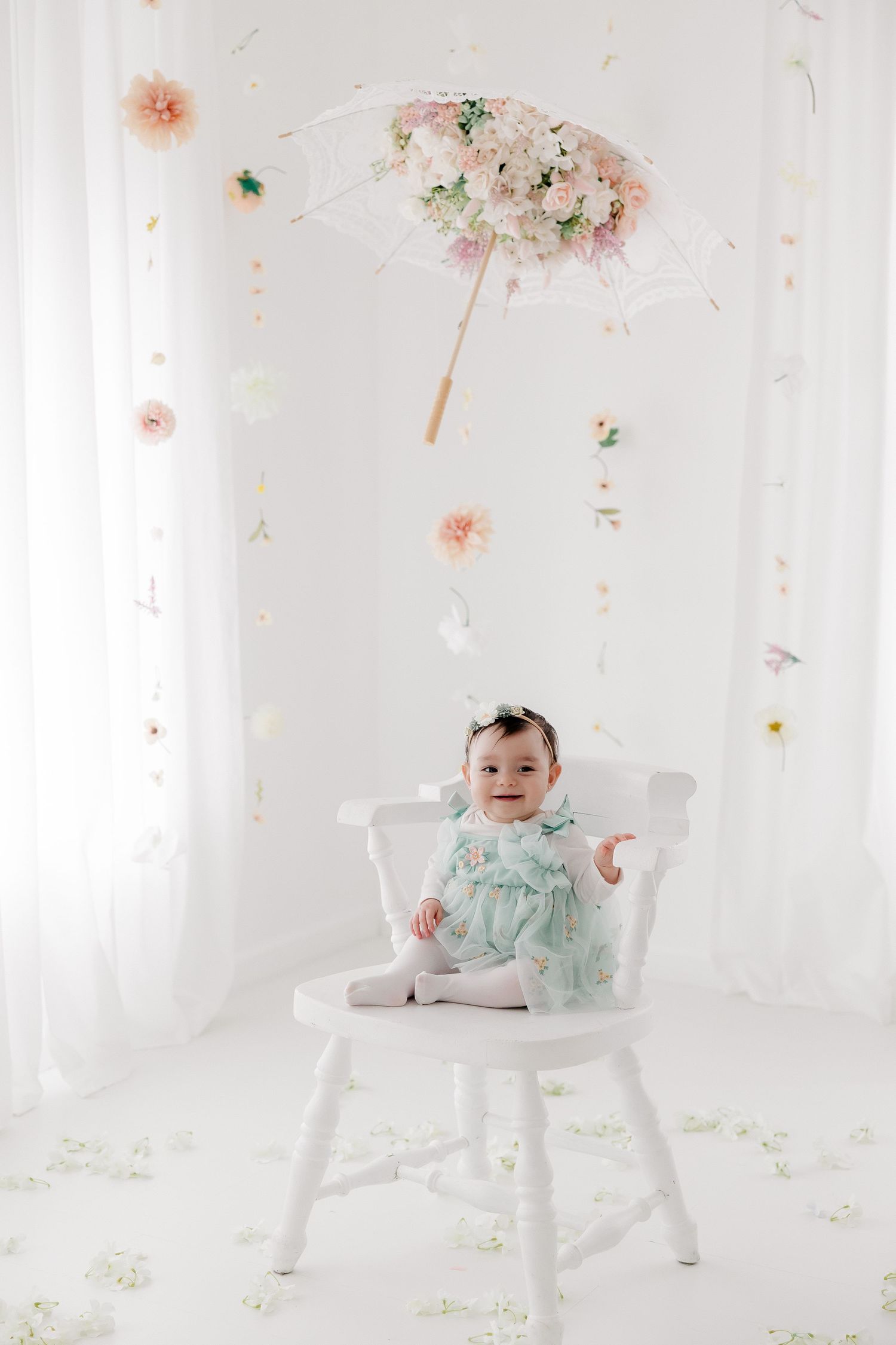 A white wooden chair with floral decorations and soft pink and mint green accents in a bright, airy setting.