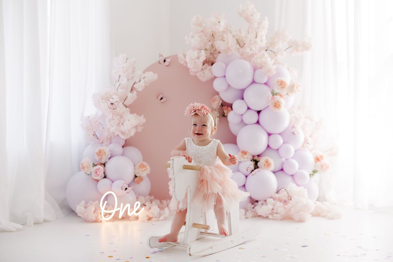 Pink and white balloon arch decorations with floral accents create a romantic backdrop for a special celebration.