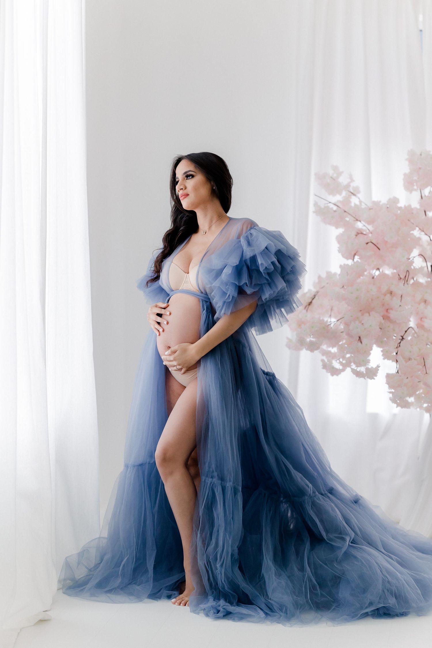 Elegant maternity portraits in flowing blue tulle gown with cherry blossoms.