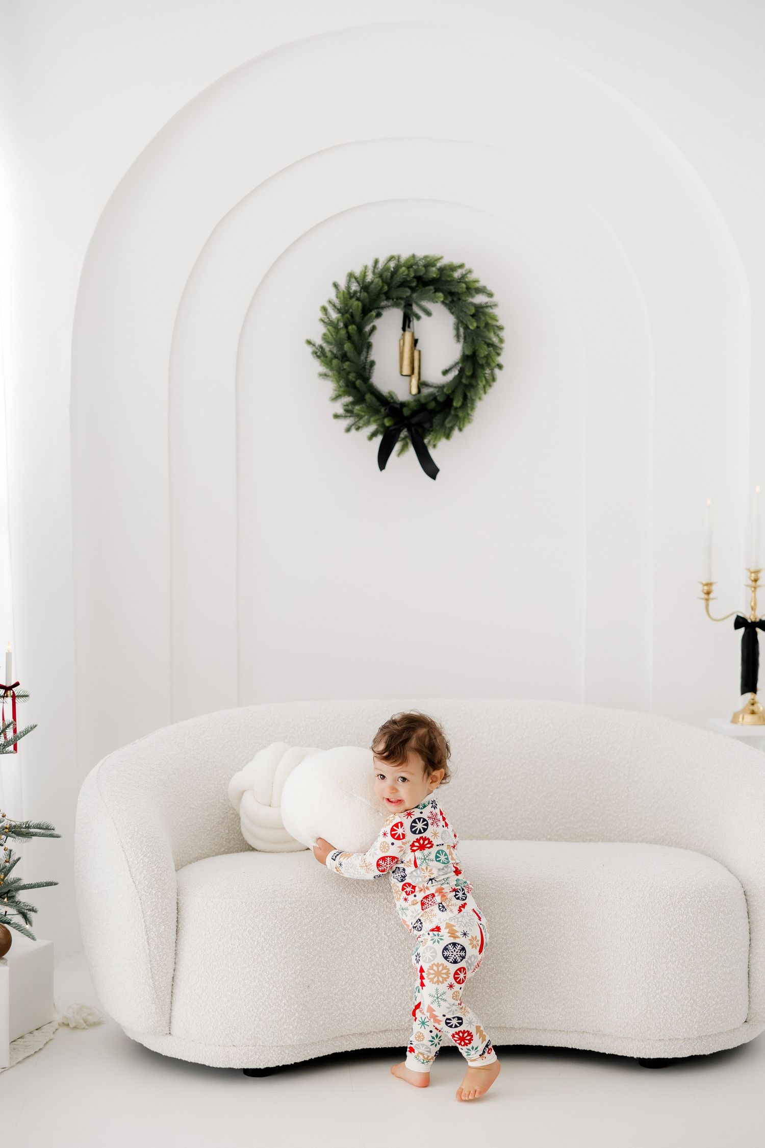 Minimalist white curved studio space with green wreaths and holiday decor.