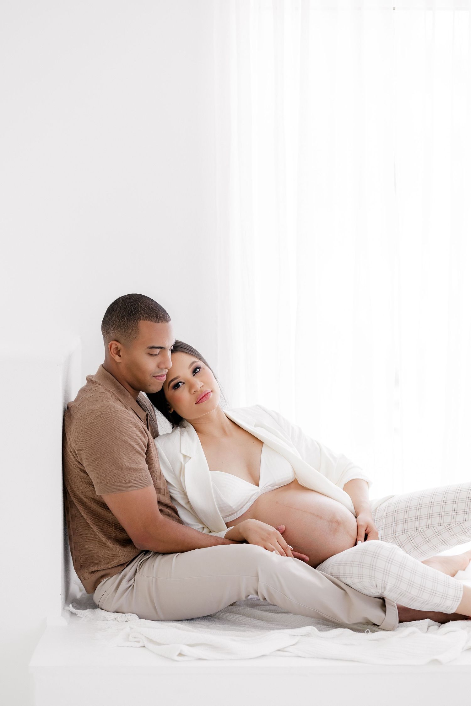 Intimate maternity portrait of couple sharing tender moment in studio setting.