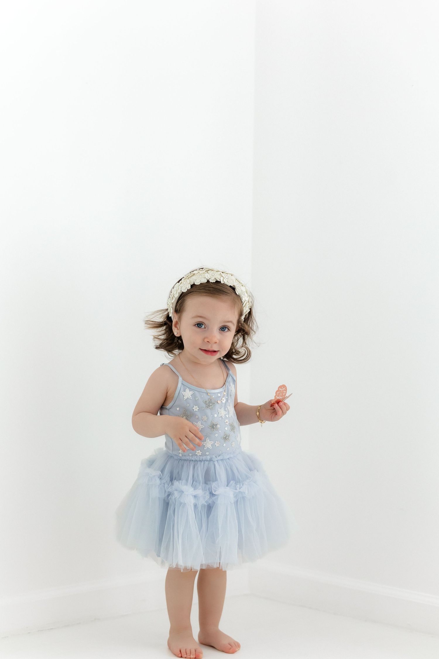 Studio portrait of light blue tulle dress and lace headband against white backdrop.