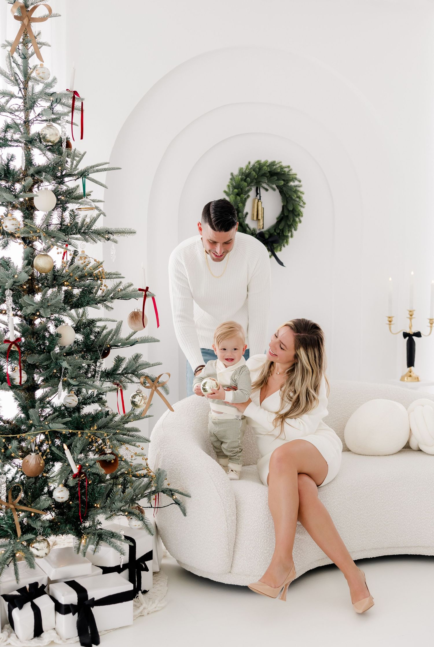 Holiday portrait session showing intimate family moments on white couch with Christmas decorations.