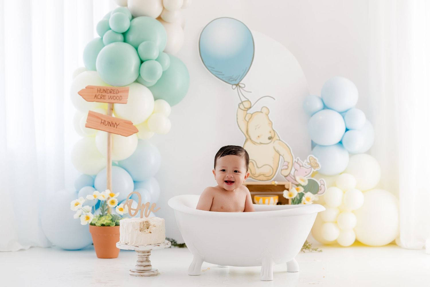Baby cake smash photo session setup with mint and blue balloons, white backdrop, and vintage decor for first birthday.
