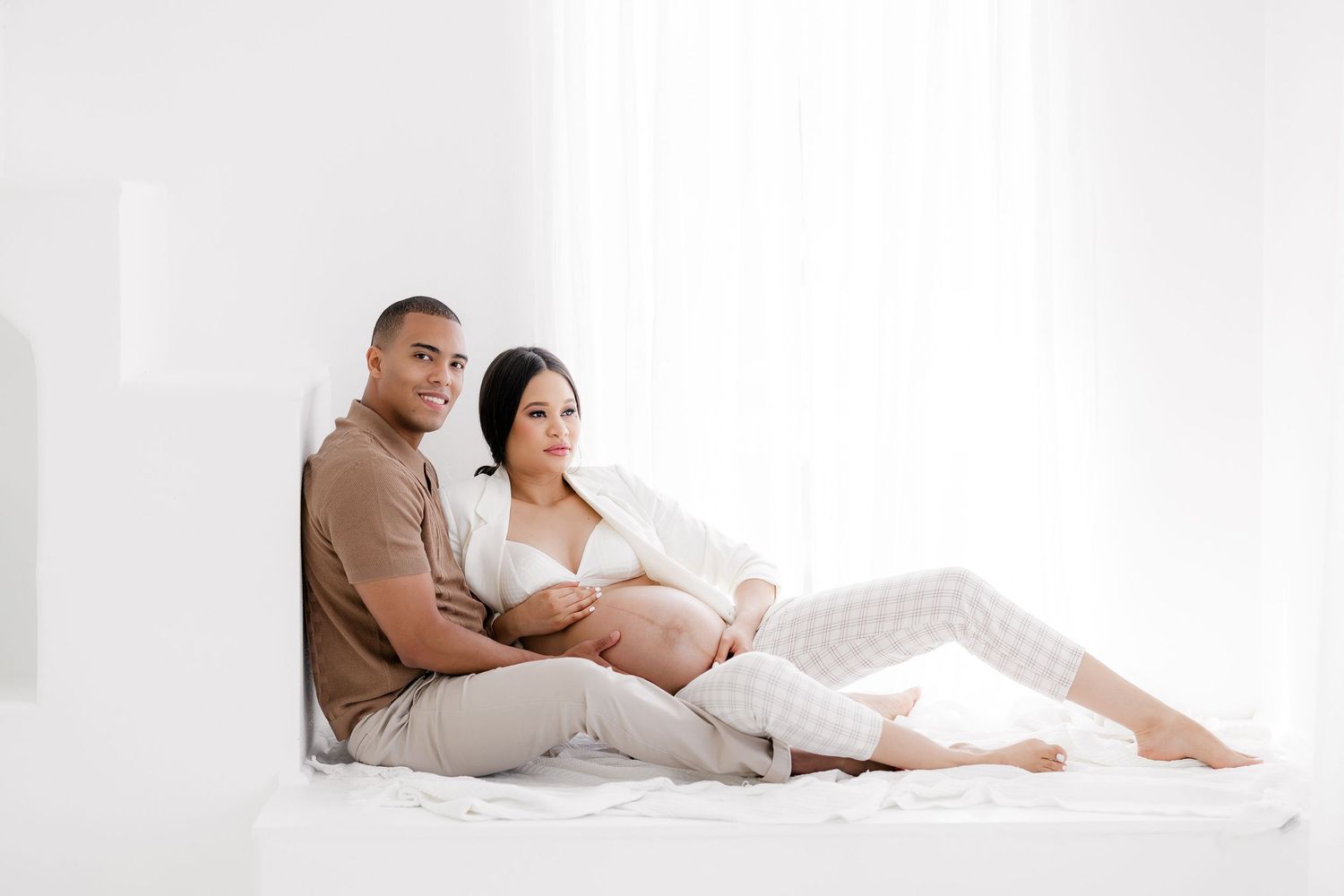 Cozy maternity session featuring family cuddling together in relaxed poses.