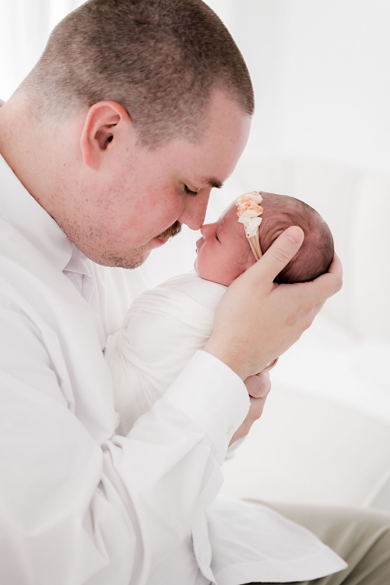 Series of intimate photographs showing parent bonding with newborn in white setting.