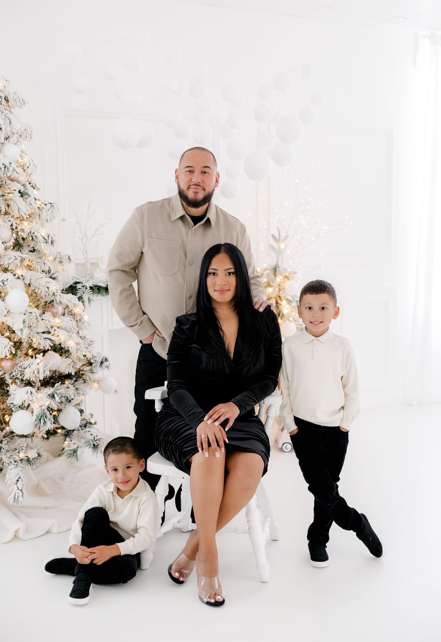 Family portrait in an elegant white studio with Christmas decorations and sparkly holiday backdrop.nj holiday mini sessions