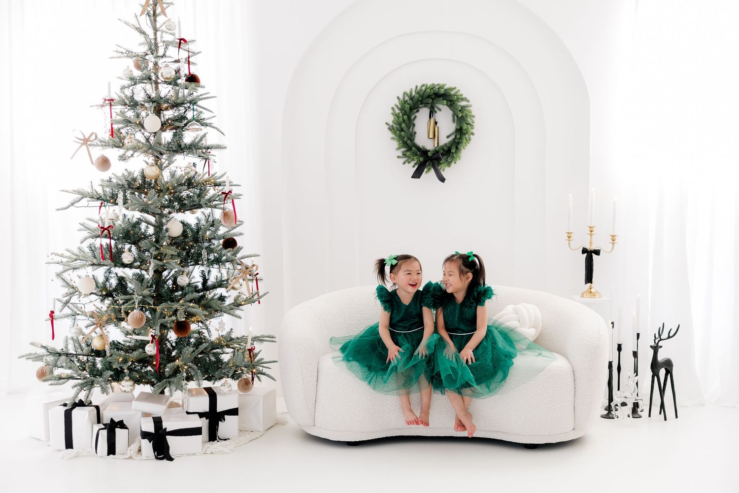 Green tutu dress displayed near white Christmas trees and holiday decorations in bright studio setting.nj holiday mini sessions