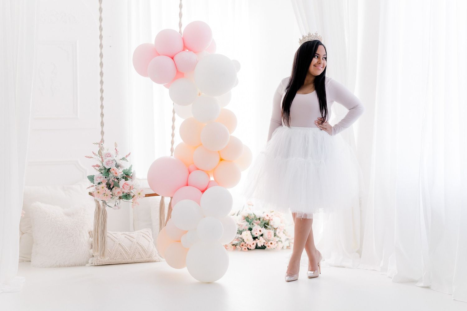 Pink and white balloons decorate a bright white room with elegant floral arrangements and romantic decor.