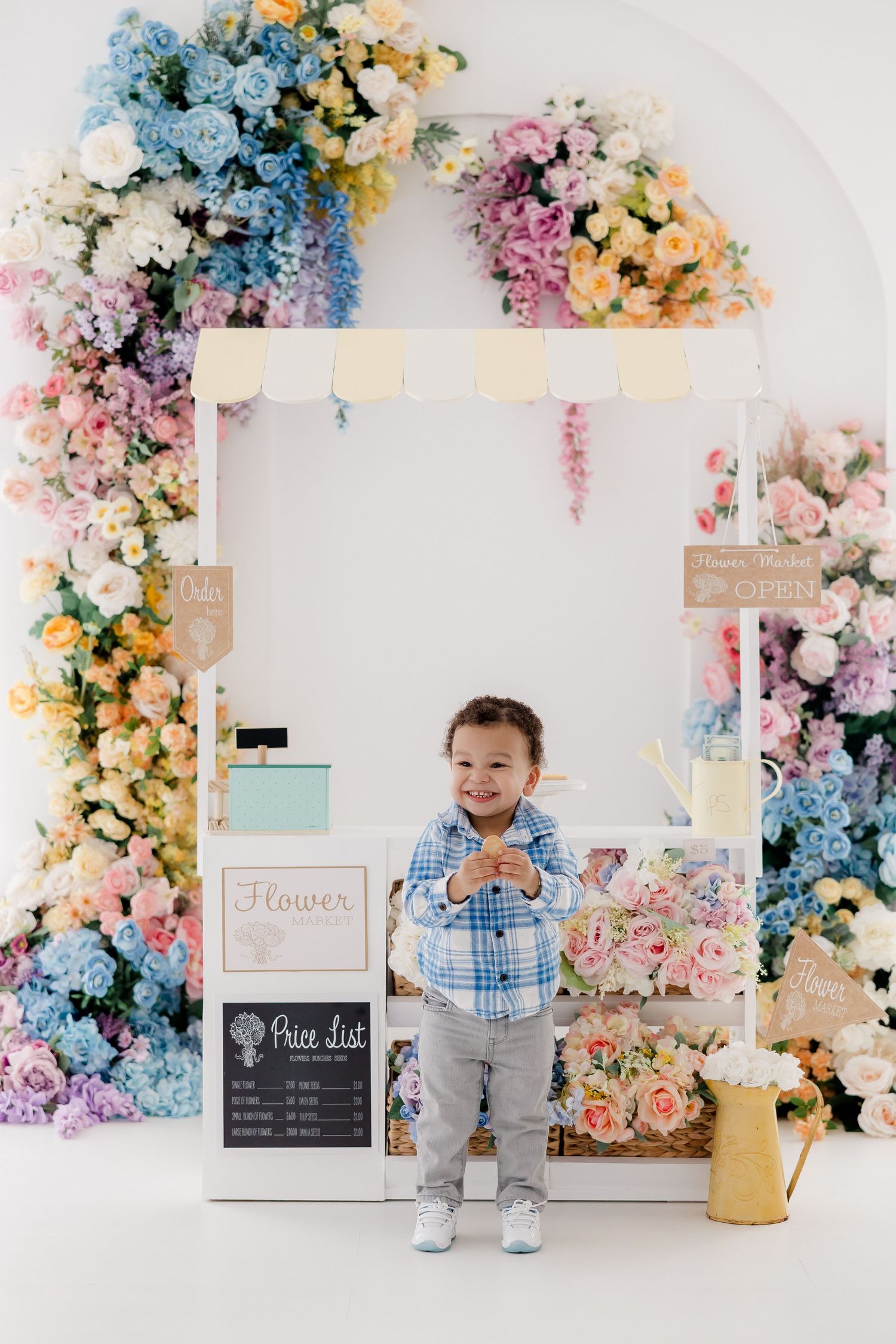 Floral backdrop with pink, blue and cream flowers arranged in an arch design for a photography studio setting.