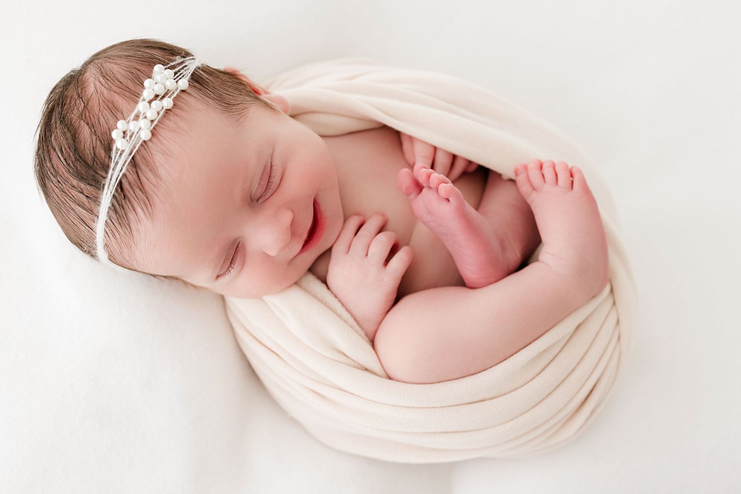 Dreamy newborn portrait in soft peach wrap with gentle natural lighting.